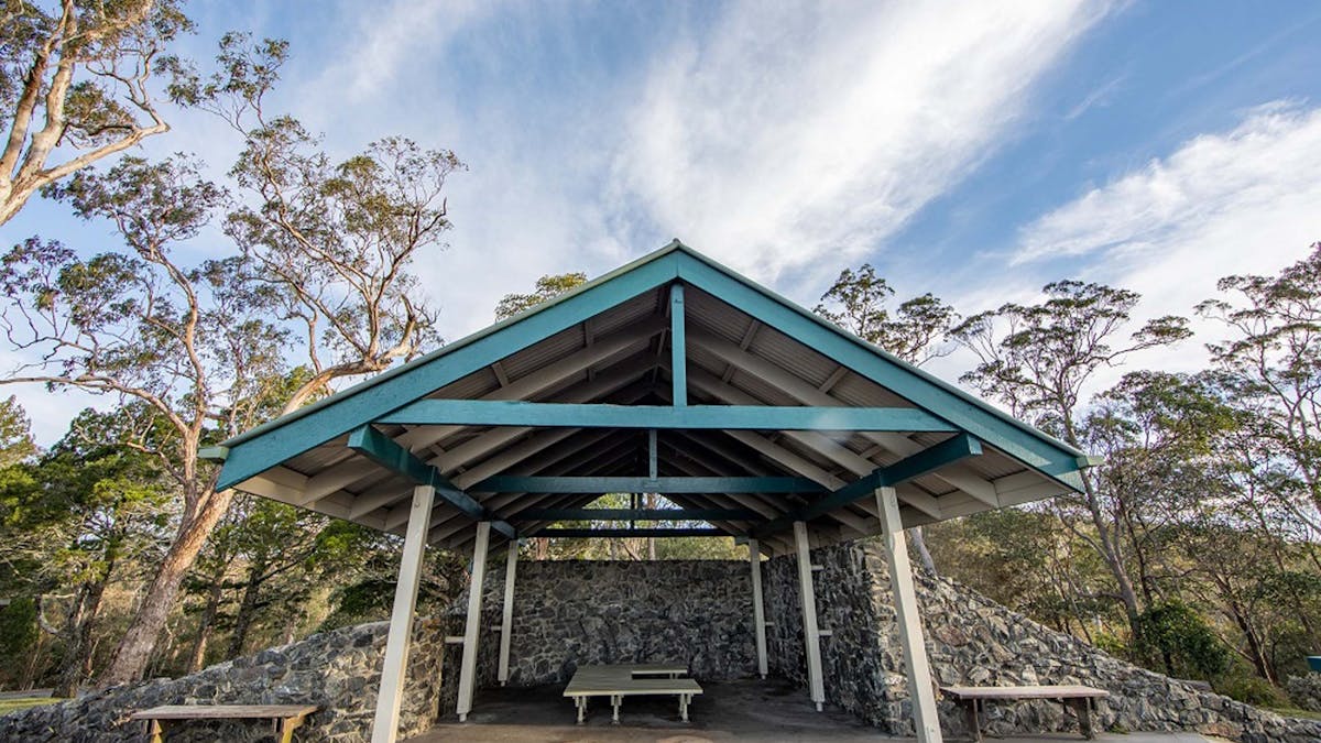 Large timber picnic shelter covering three picnic tables