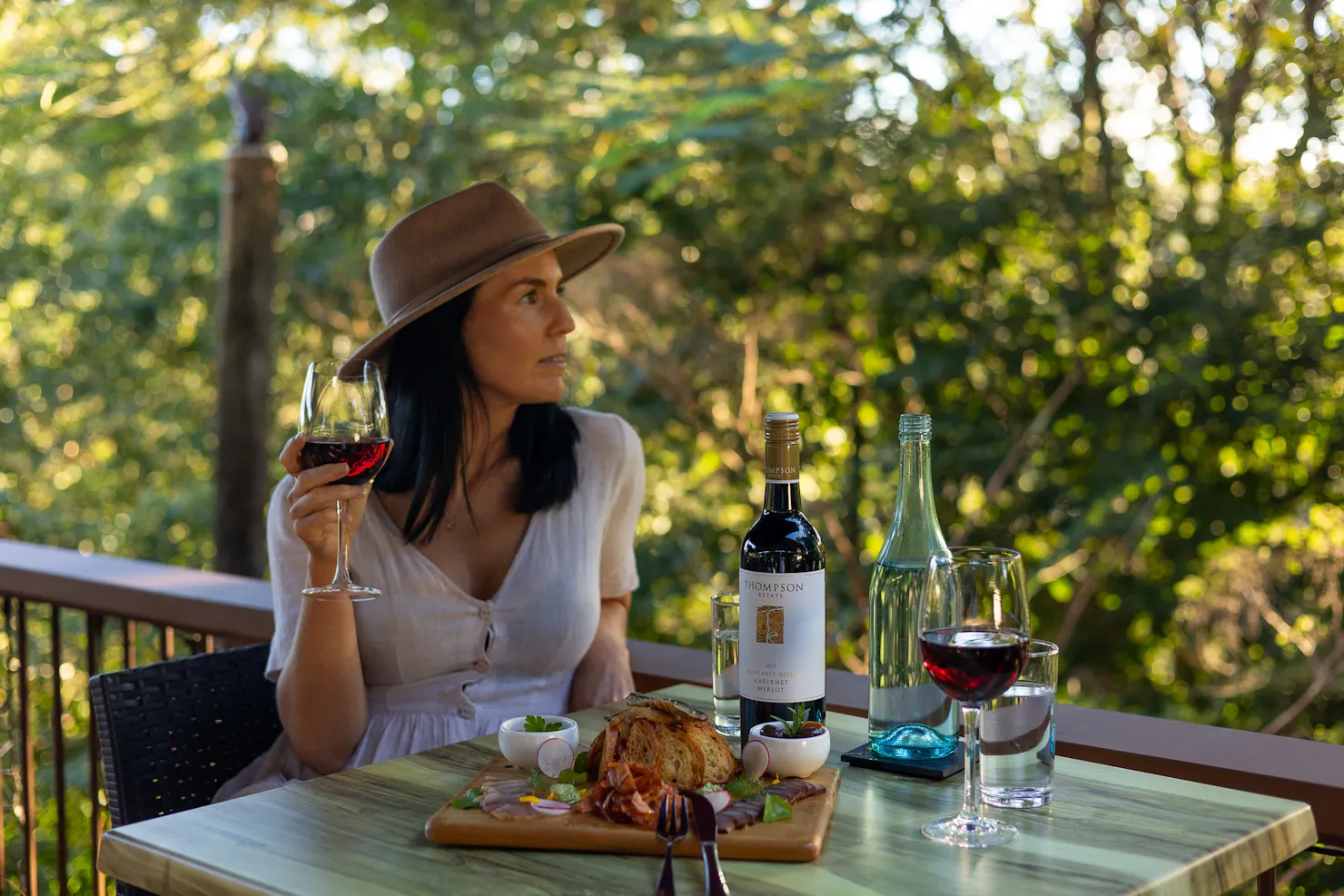 A Kondalilla Restaurant guest dining on the deck, enjoying the charcuterie board with a red wine..
