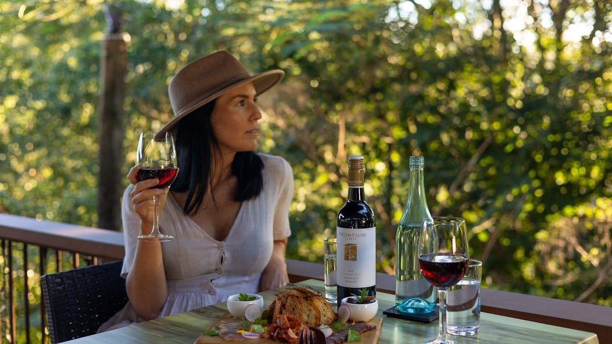 A Kondalilla Restaurant guest dining on the deck, enjoying the charcuterie board with a red wine..