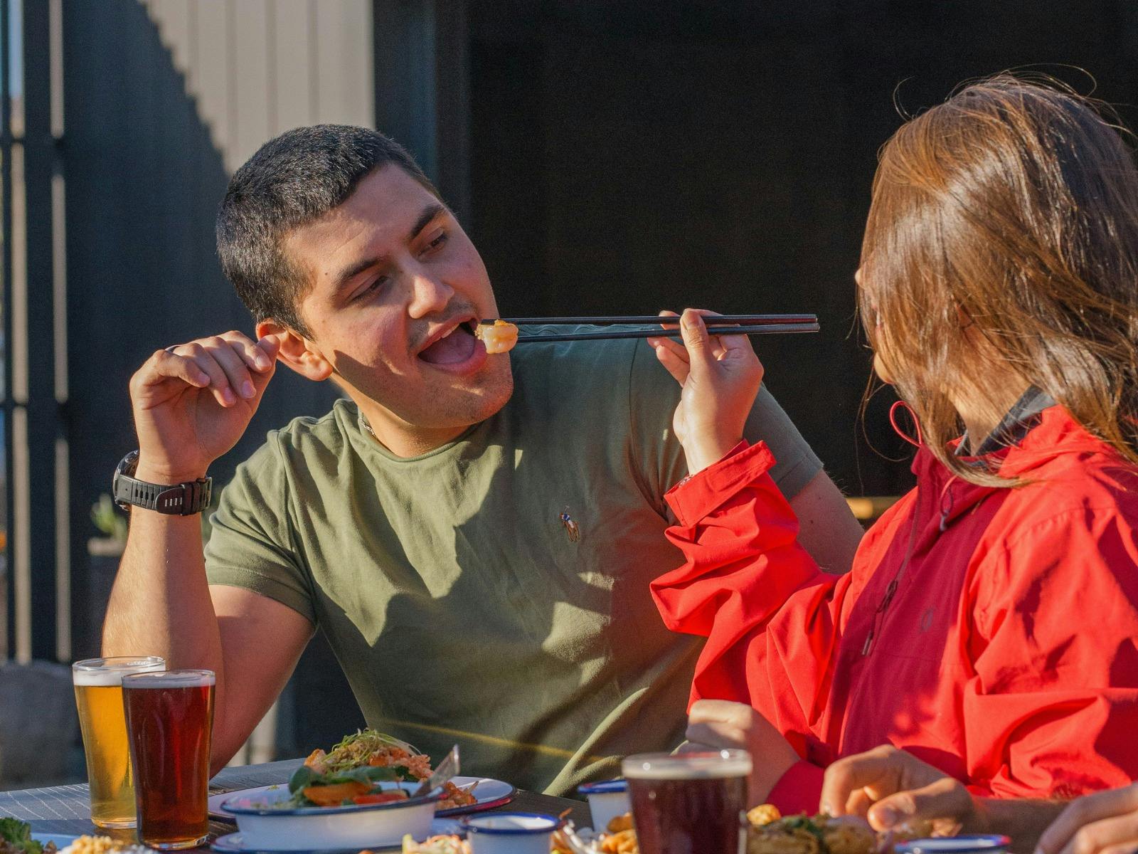 Two customers sharing Thai food with chopsticks at Easy Tiger in St Helens.