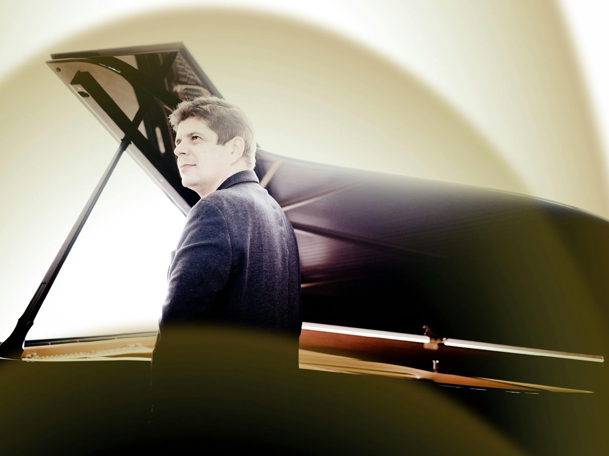 Pianist Javier Perianes standing beside an open grand piano