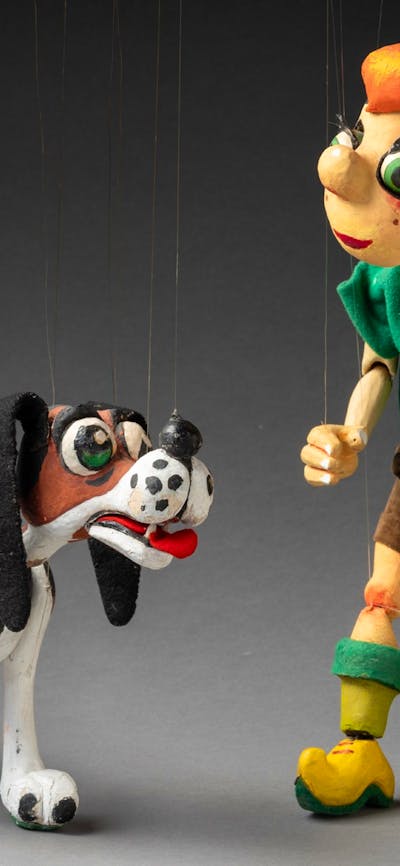 A string puppet of a boy with orange hair and a dog.