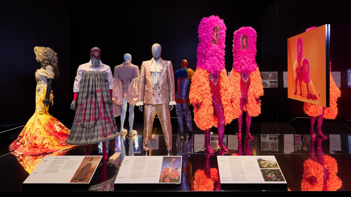 Vibrantly dressed mannequins are positioned along a reflective black platform.