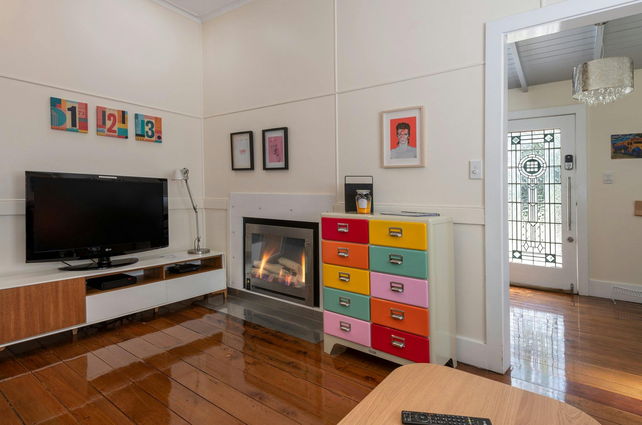 Living area with gas fireplace, flat-screen TV and colourful furnishings.