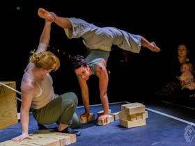 one acrobat is upside down while another pulls her over