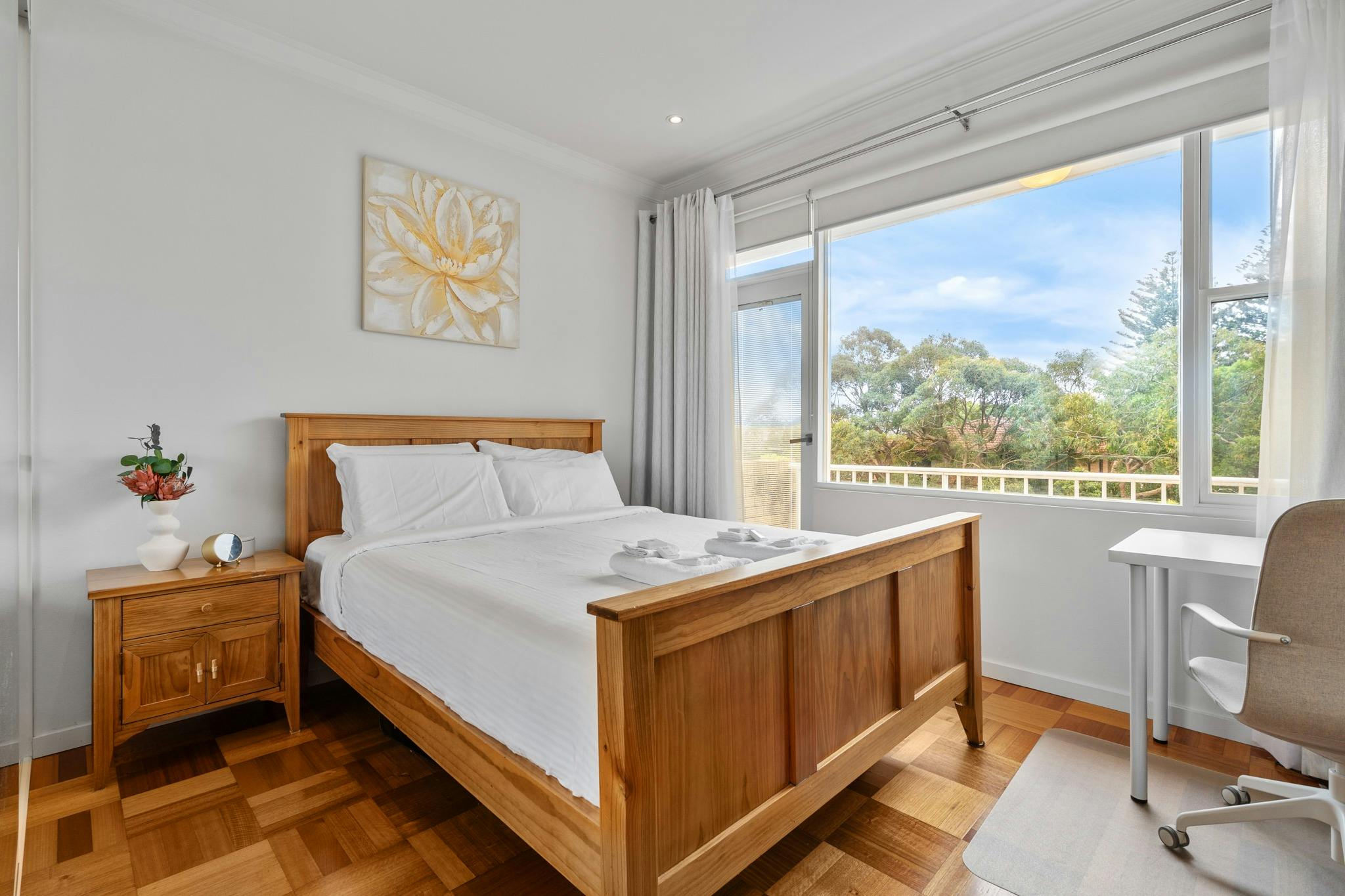 明亮的臥室配有木製家具和俯瞰綠色風景的大窗戶。