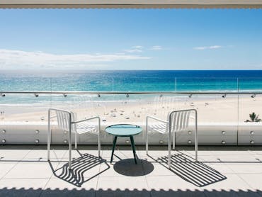 Private Kirra Point balcony with ocean views, beach access, and seating for two under blue skies. Private Kirra Point balcony with ocean views, beach access, and seating for two under blue skies.