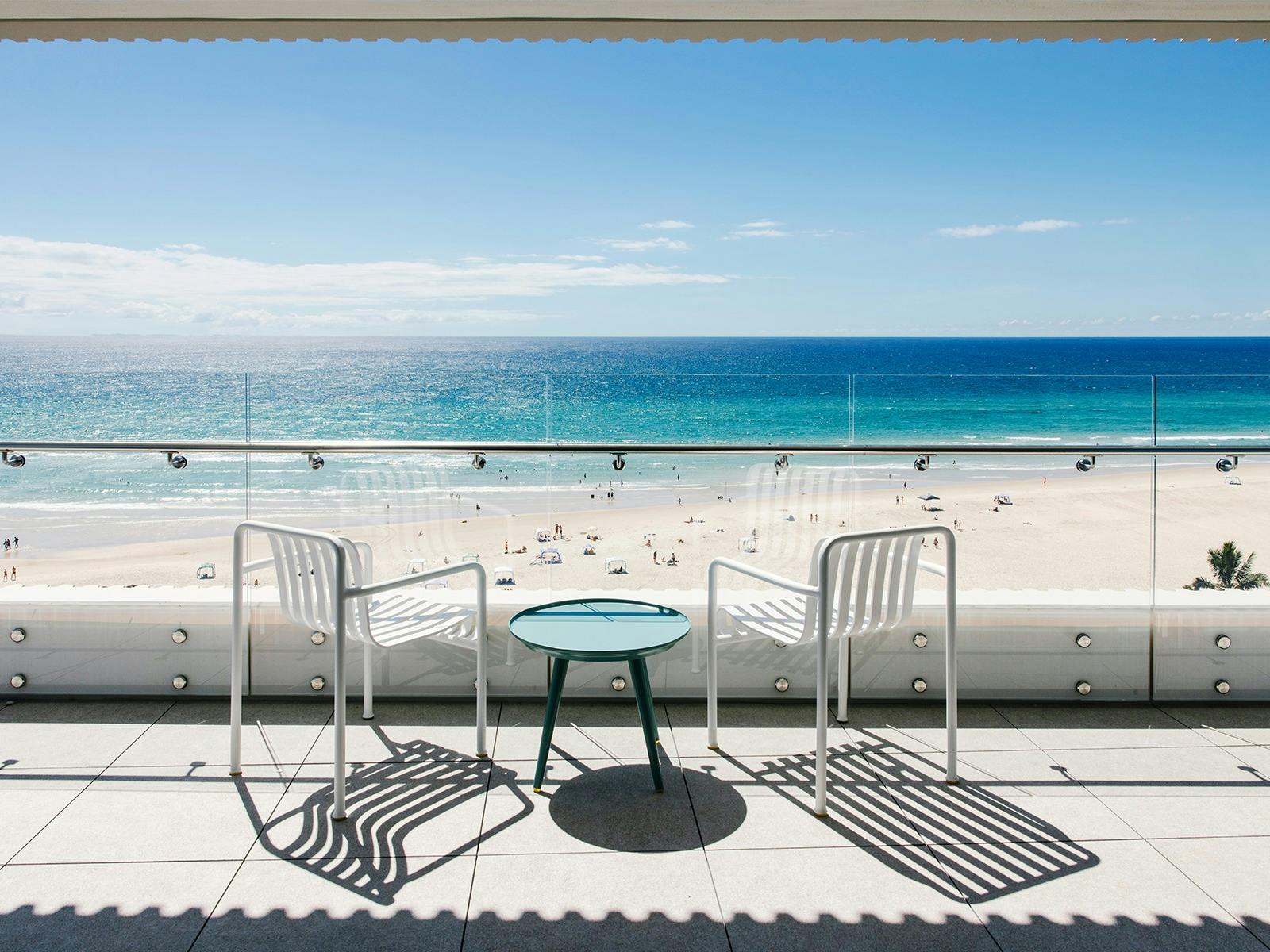 Private Kirra Point balcony with ocean views, beach access, and seating for two under blue skies. Private Kirra Point balcony with ocean views, beach access, and seating for two under blue skies.