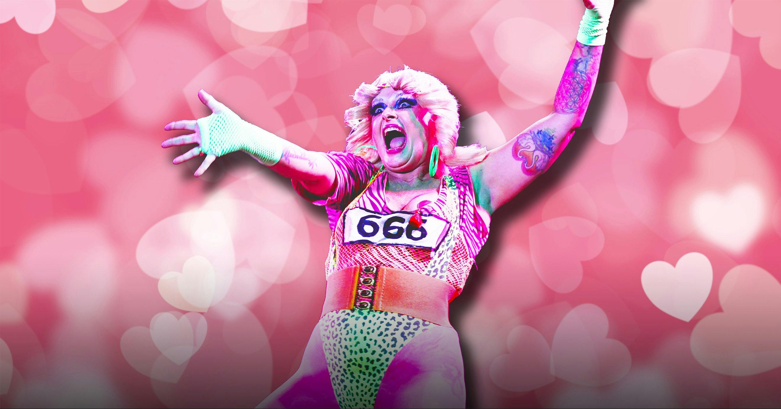 A performer holding her hands out into the crowd in front of a heart filled background