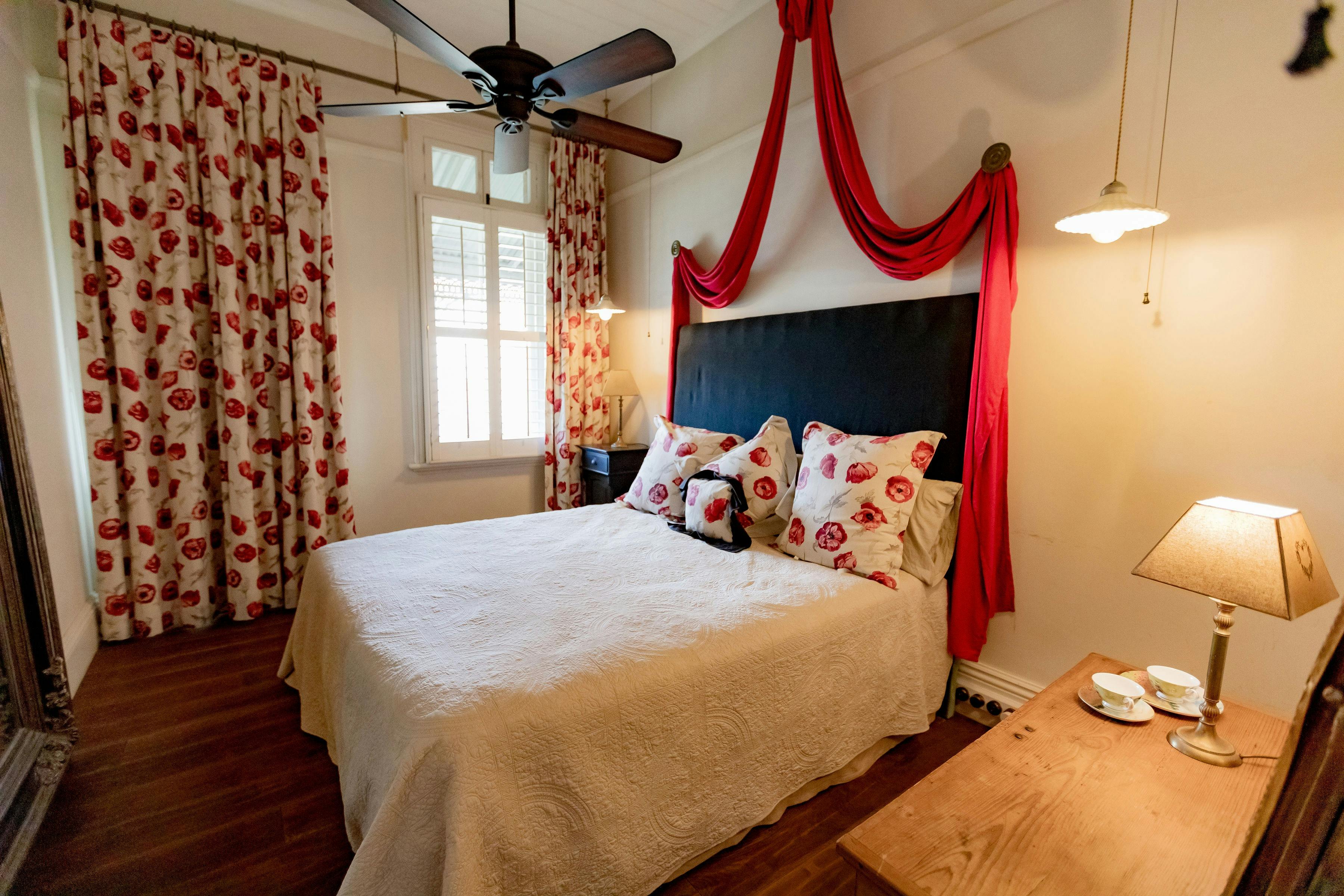 Large queen bed in a room with wooden floors and natural light