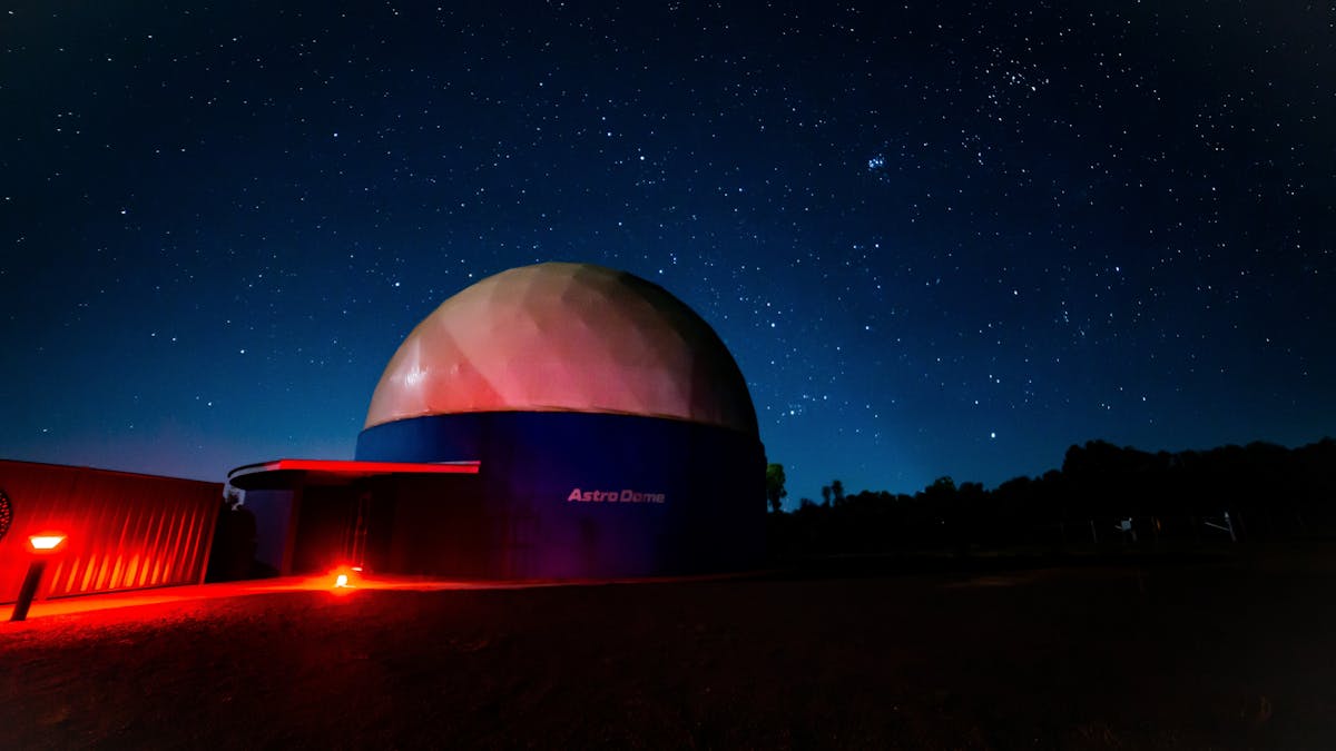 Massive dome shaped planetarium backdropped by starry night sky.