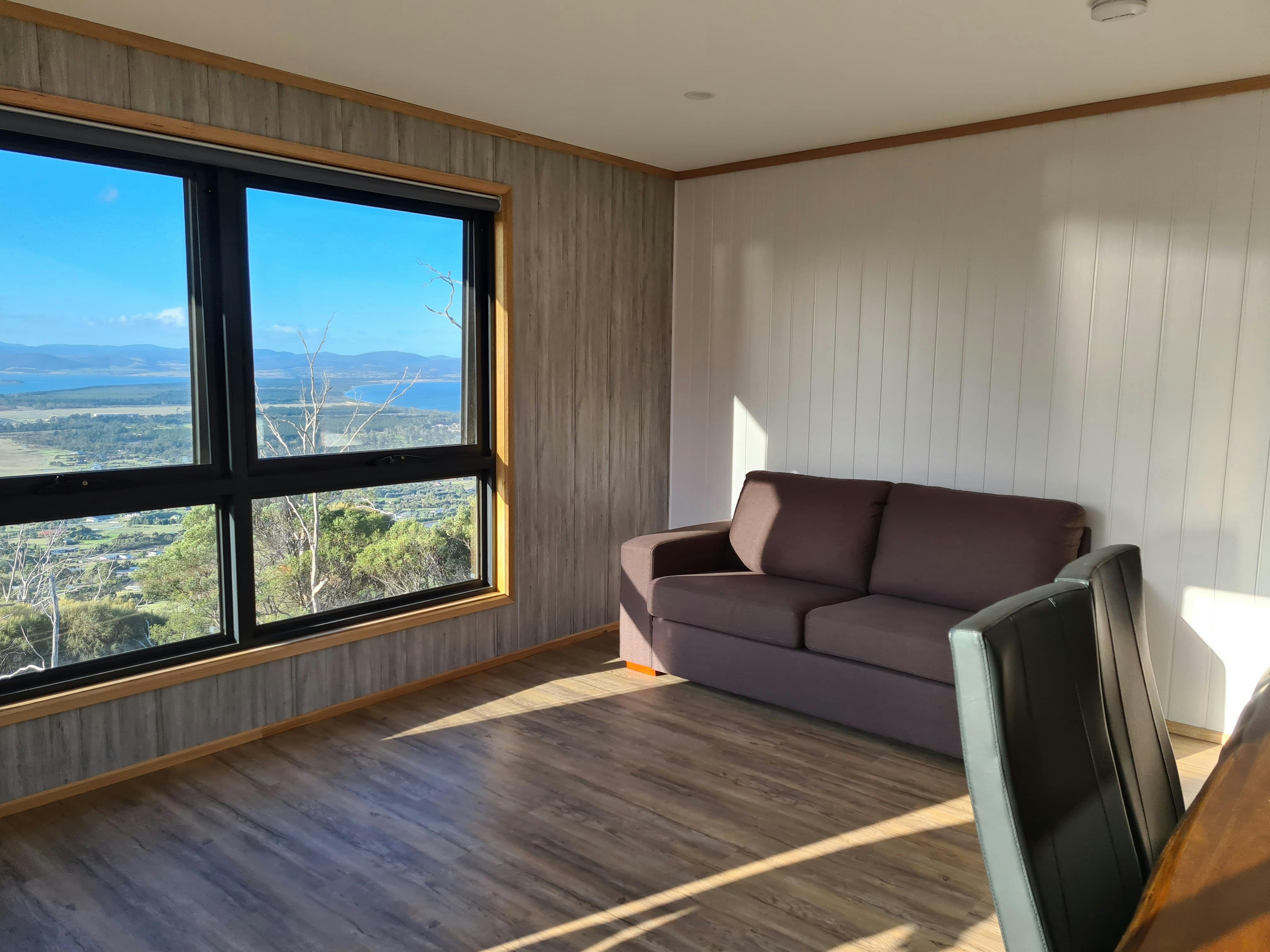 Comfortable lounge room with large windows overlooking the landscape