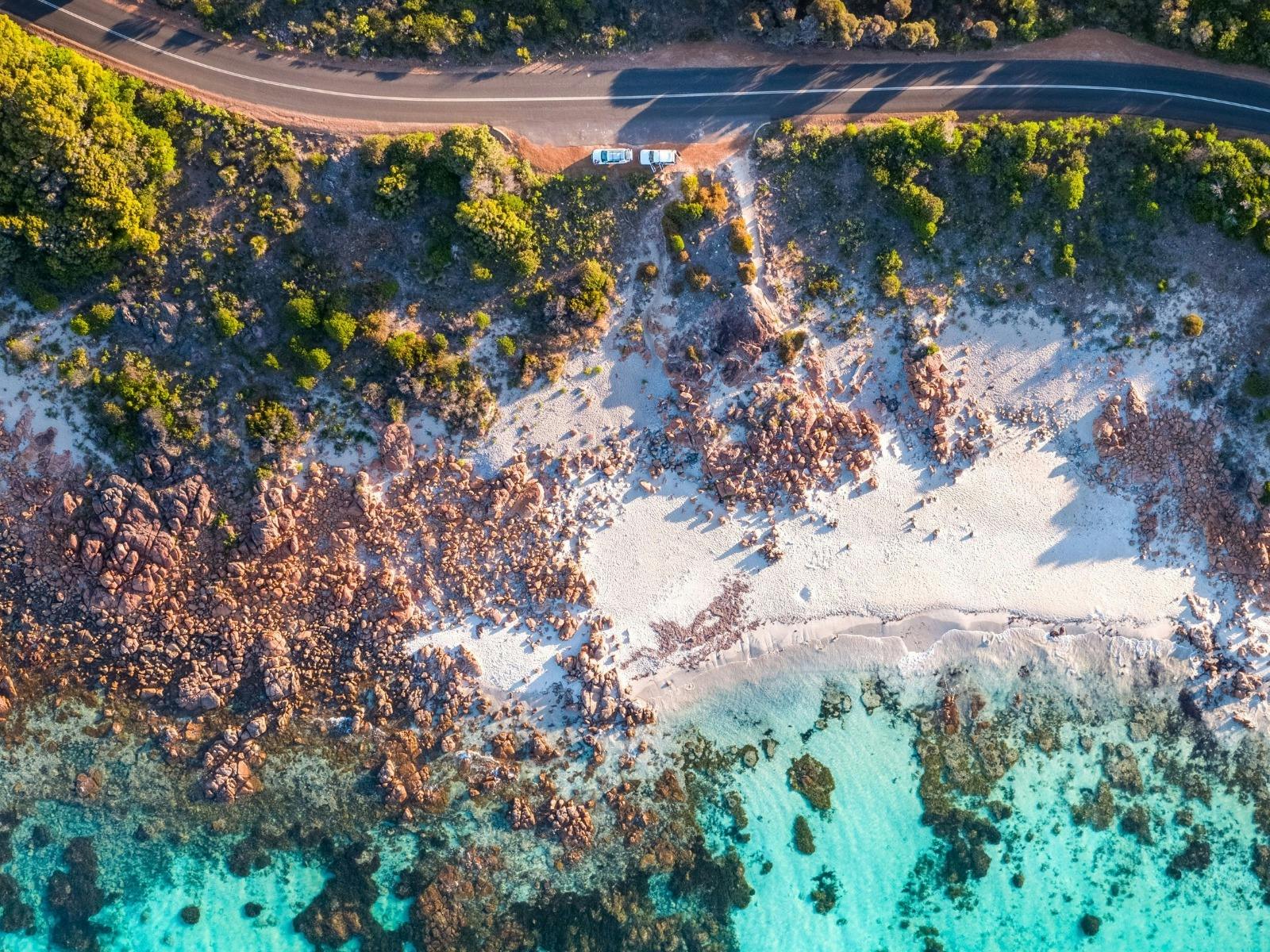 Aerial view of a rugged coastline, where lush green trees frame the entrance to the sea