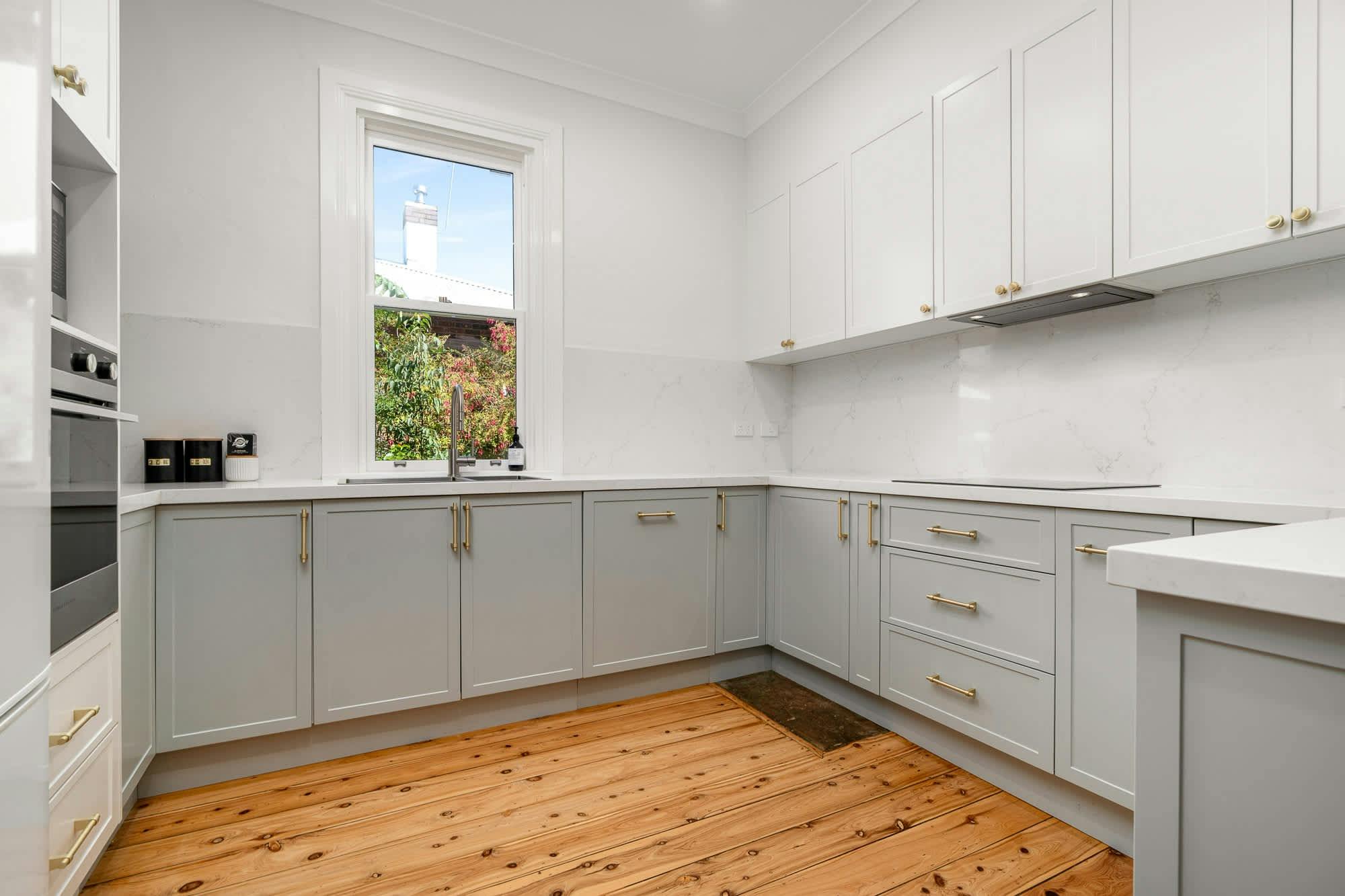 Kitchen with grey and white cabinets and wooden floors