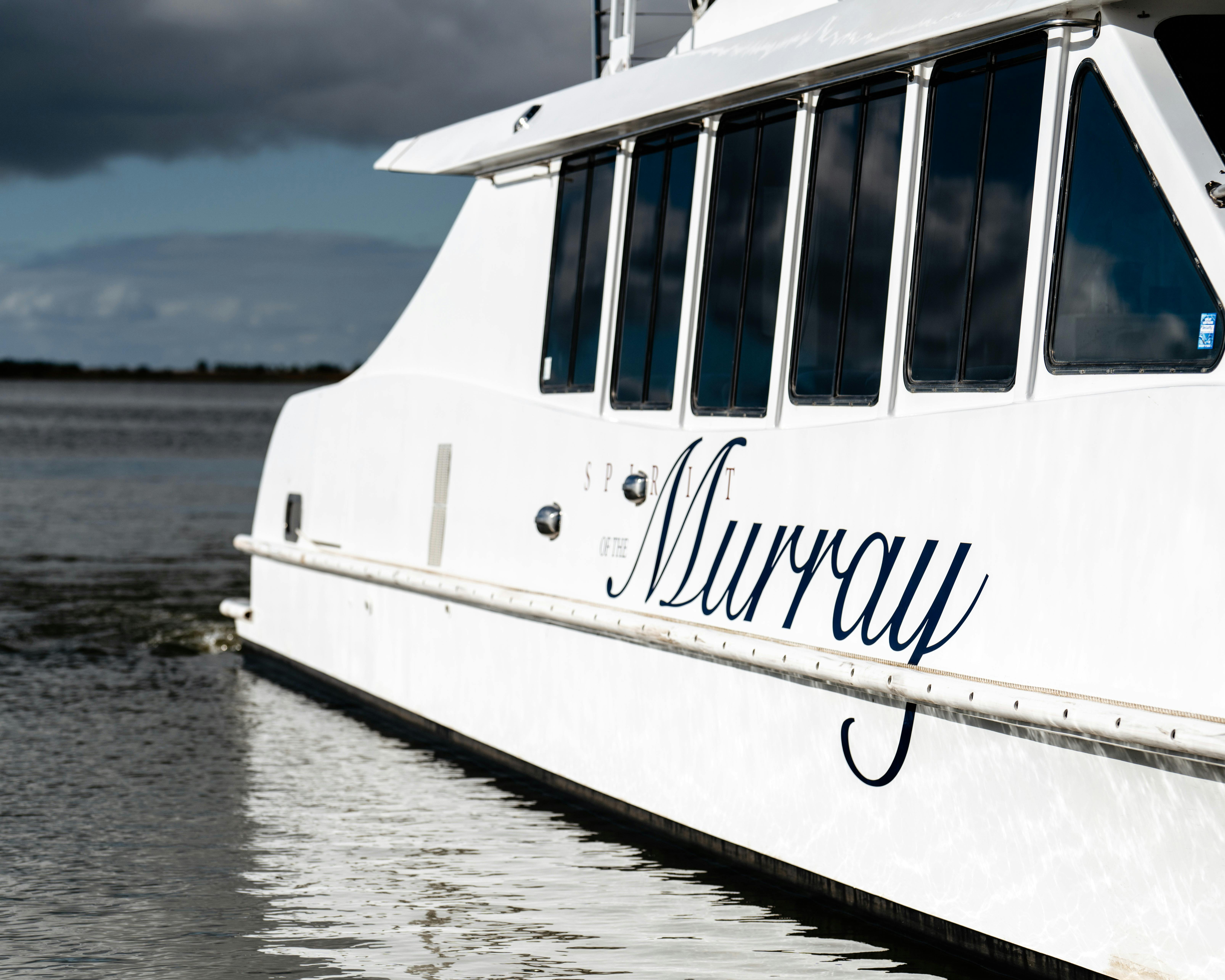 Close-up of the "Spirit of the Murray" boat on water, with a cloudy sky in the background