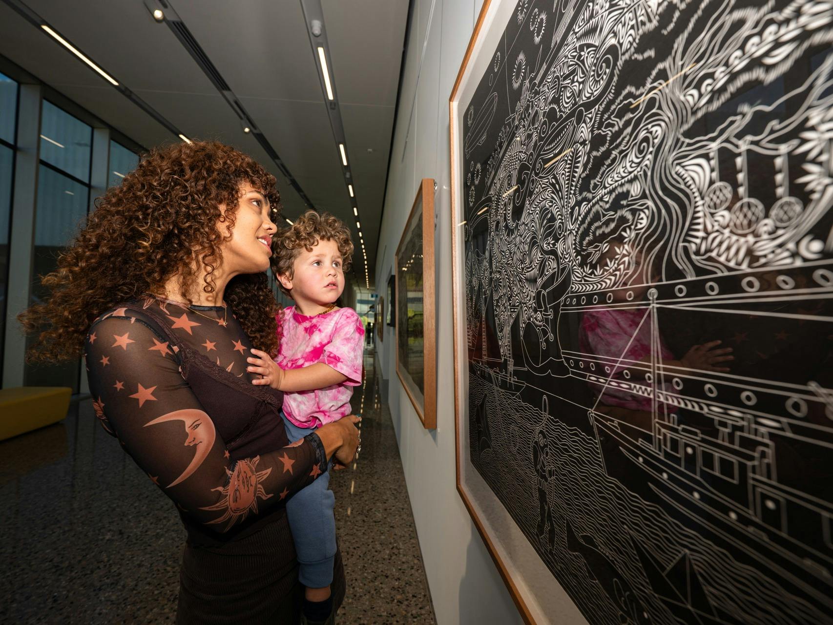 A woman and her young child look at a painting