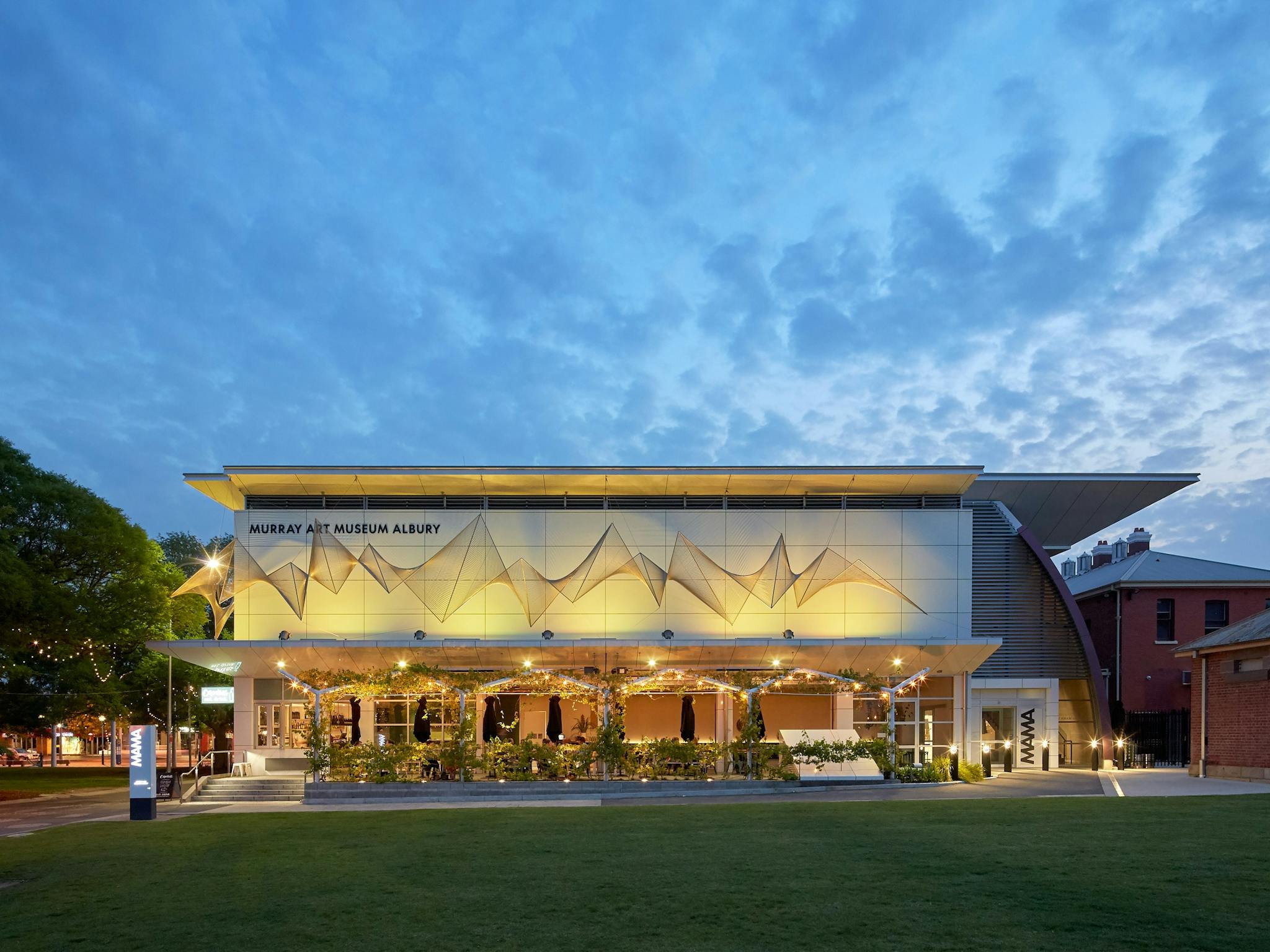 The exterior of a large white building reading 'Murray Art Museum Albury' behind a green field