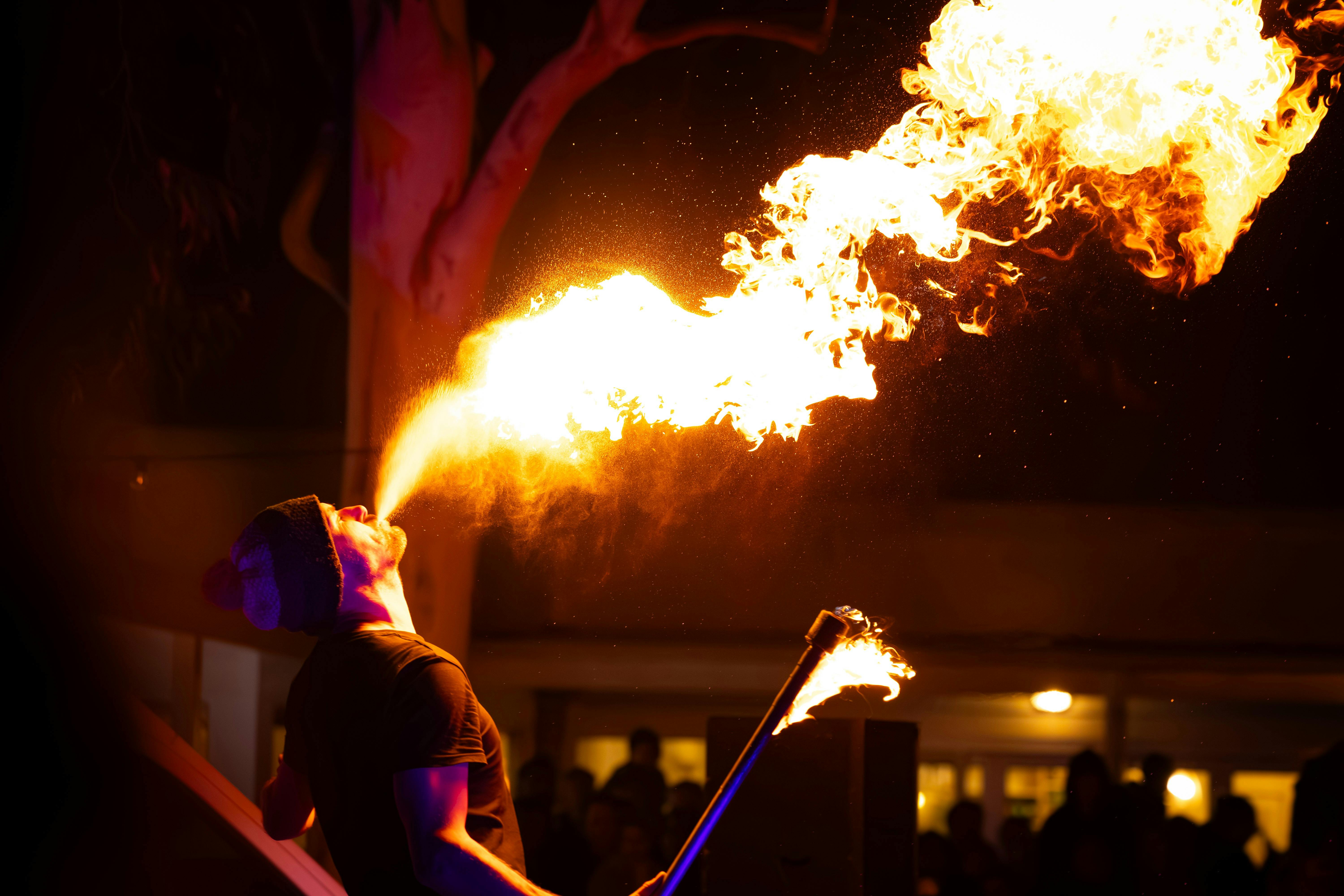 A performer breathing fire into the dark night sky