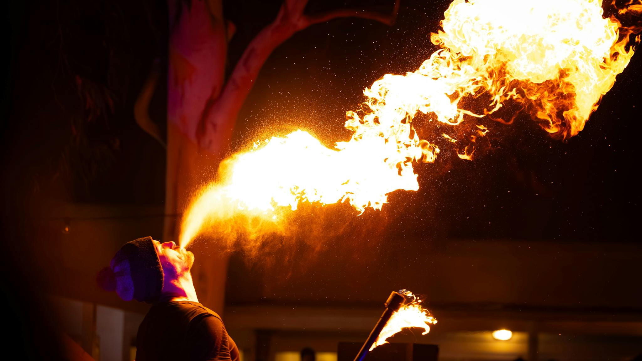 A performer breathing fire into the dark night sky