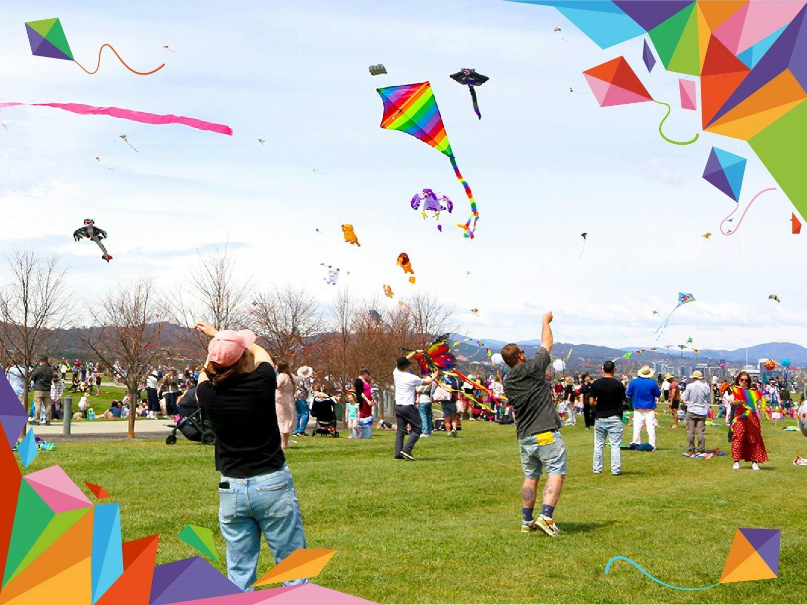 Crowds of families fly colourful kites on a large grassy lawn at the arboretum