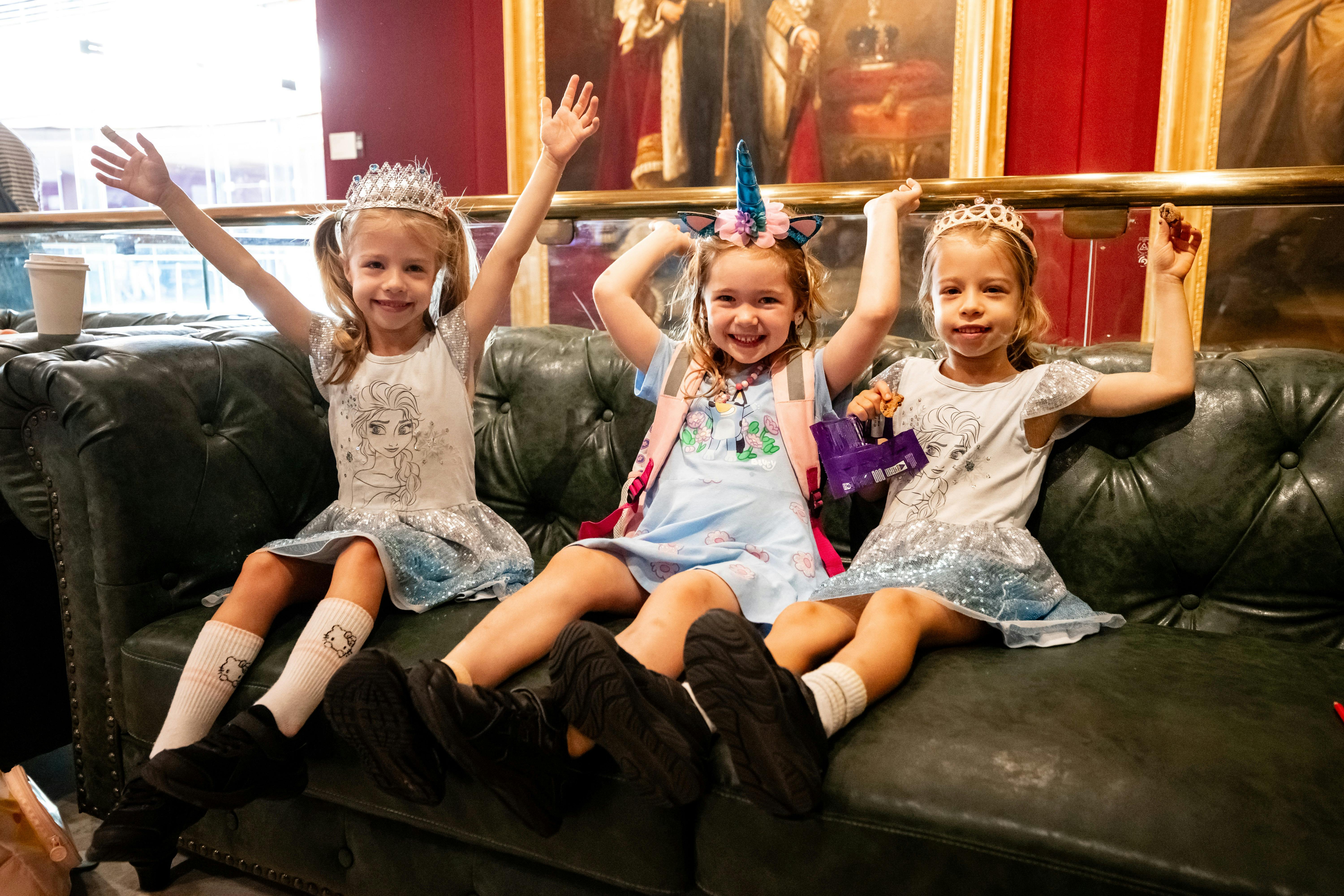 3 young girls dressed with princess  crowns sit on a sofa in NSW Parliament on Family Fun Day