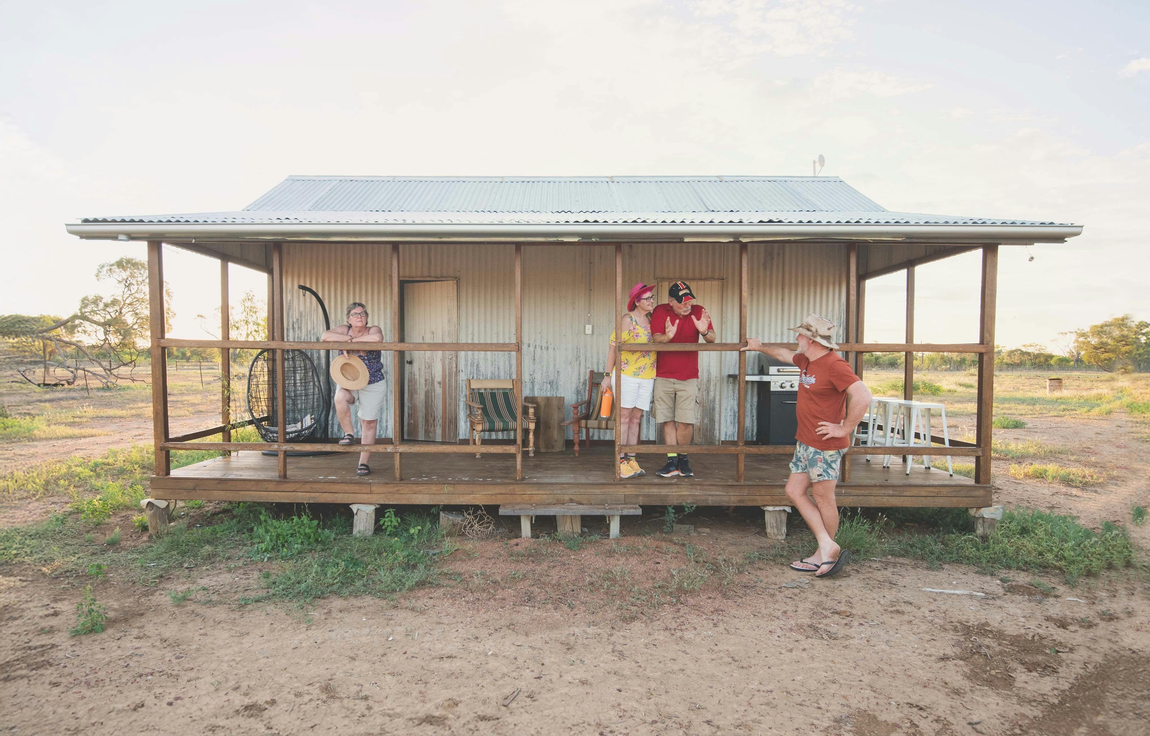 People standing on the deck of a rustic cottage