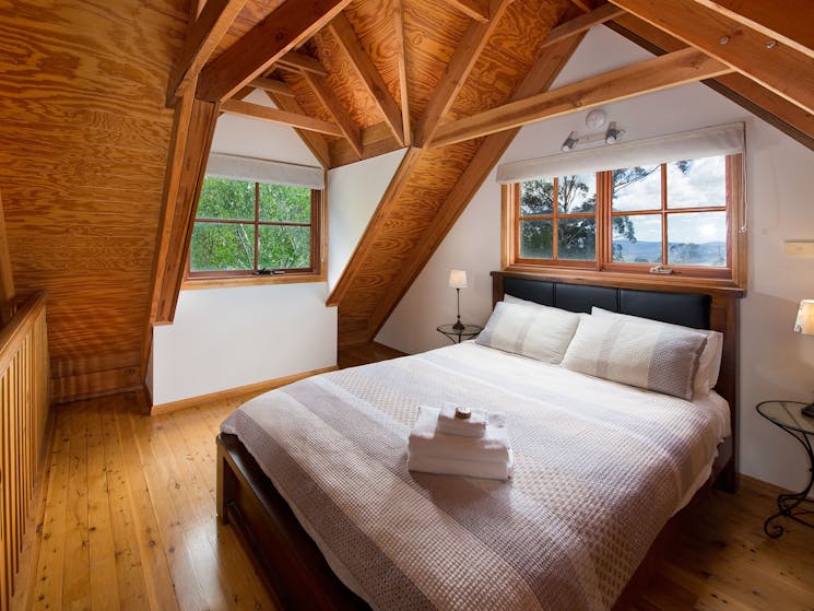 The loft bedroom with distant views of the Kanimbla valley. Classic Blue Mountains cottage style. Premium A.H.Beard Kingcoil queen mattress.