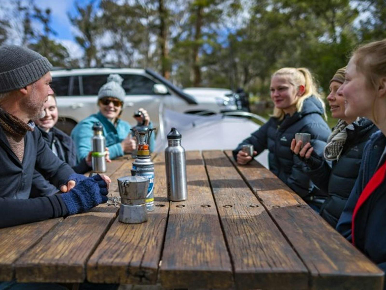 A group of friends sitting at a picnic table at Dangars Gorge campground in Oxley Wild Rivers