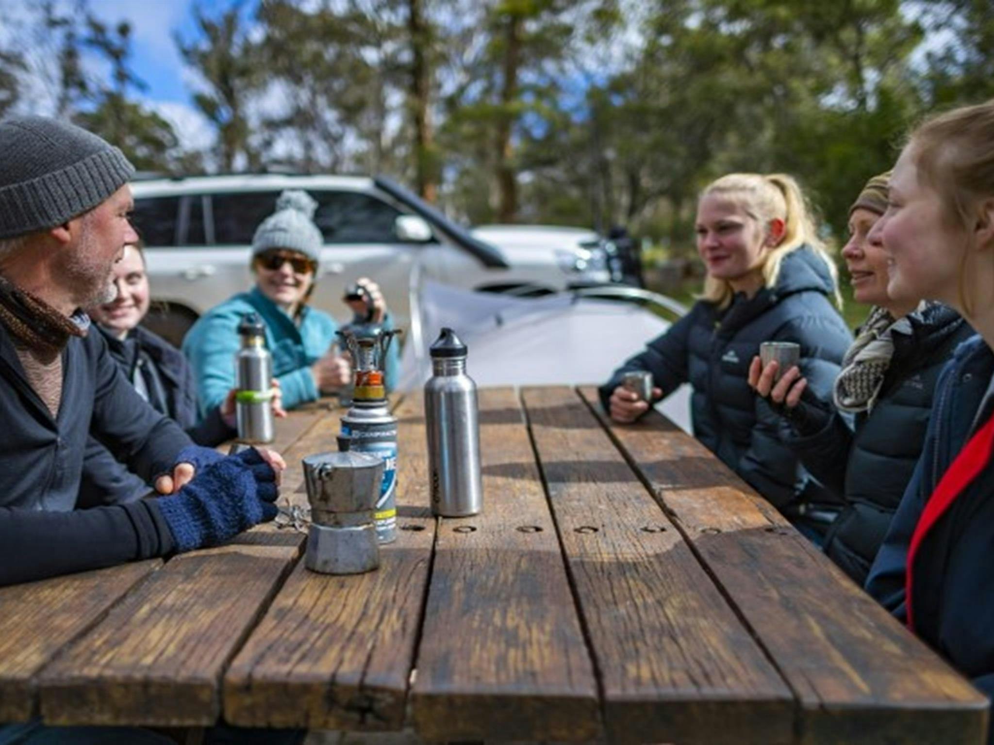 Eine Gruppe von Freunden sitzt an einem Picknicktisch auf dem Campingplatz Dangars Gorge in Oxley Wild Rivers.