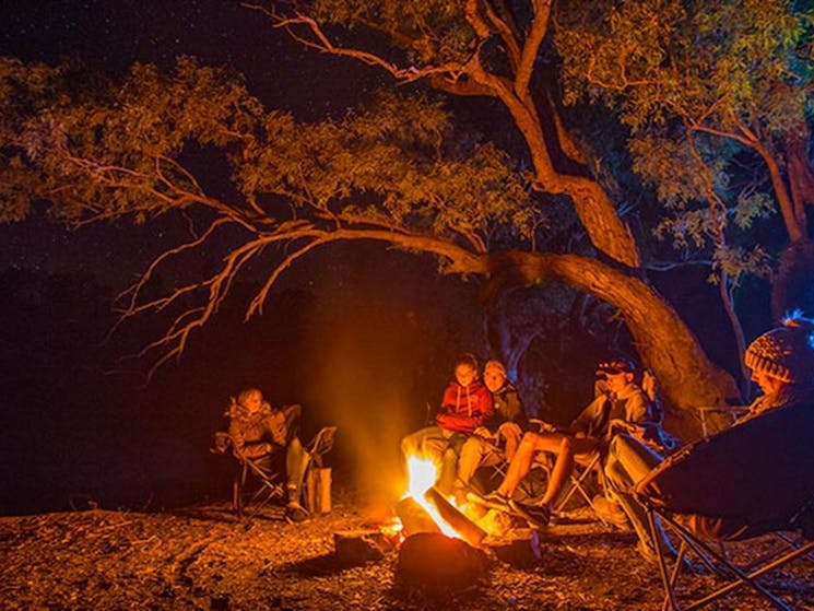 A family sit around a campfire at Darling River campground, Toorale National Park. Photo: Joshua