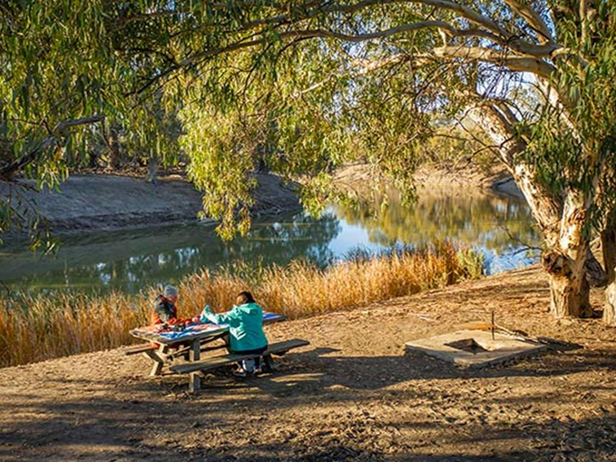 Menschen beim Picknick am Flussufer auf Campingplatz 22 des Darling River Campingplatzes. Foto: John