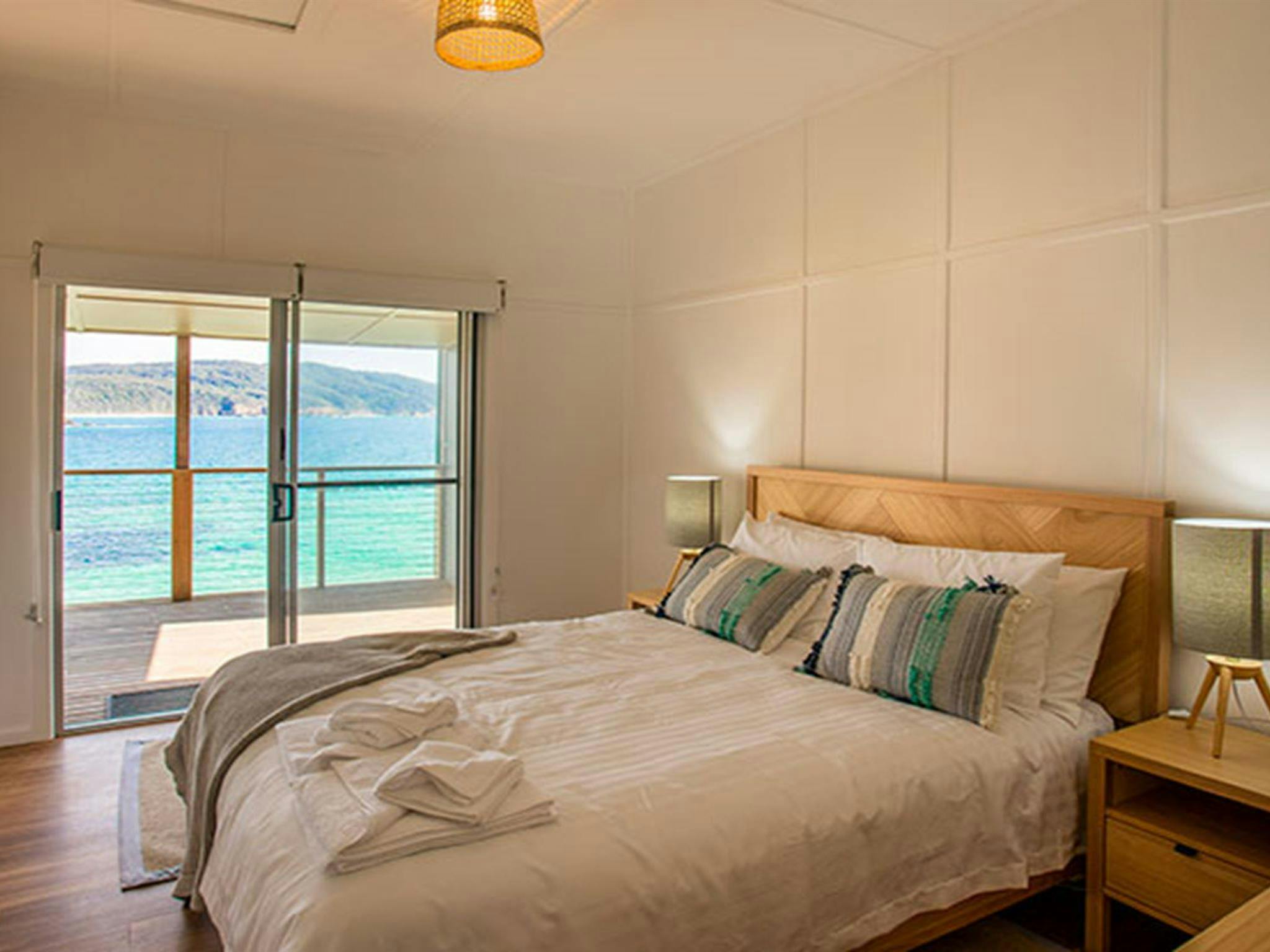 A bedroom with queen bed and ocean views in Davies Cottage. Photo: John Spencer &copy; DPIE