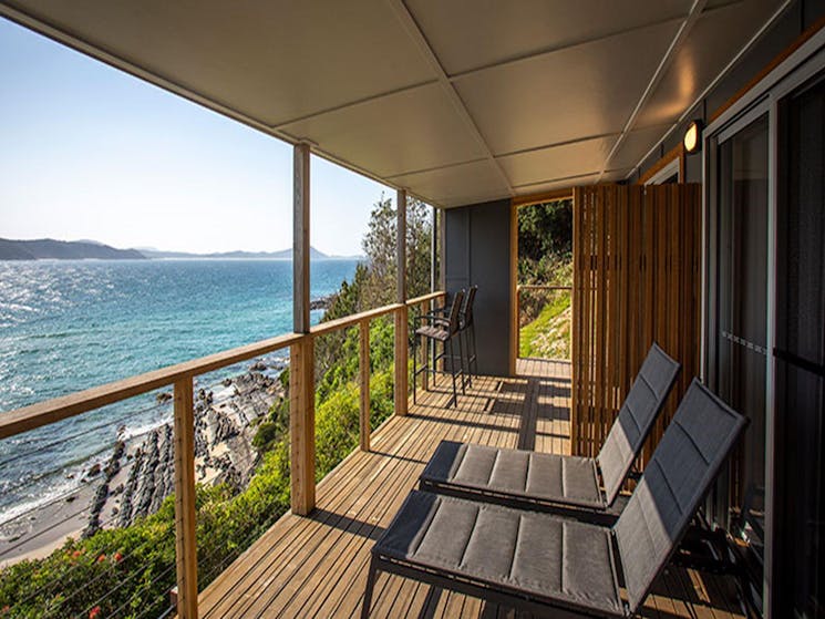 Sun lounges on the balcony of Davies Cottage overlooking Boat Beach and Sugarloaf Bay. Photo: John