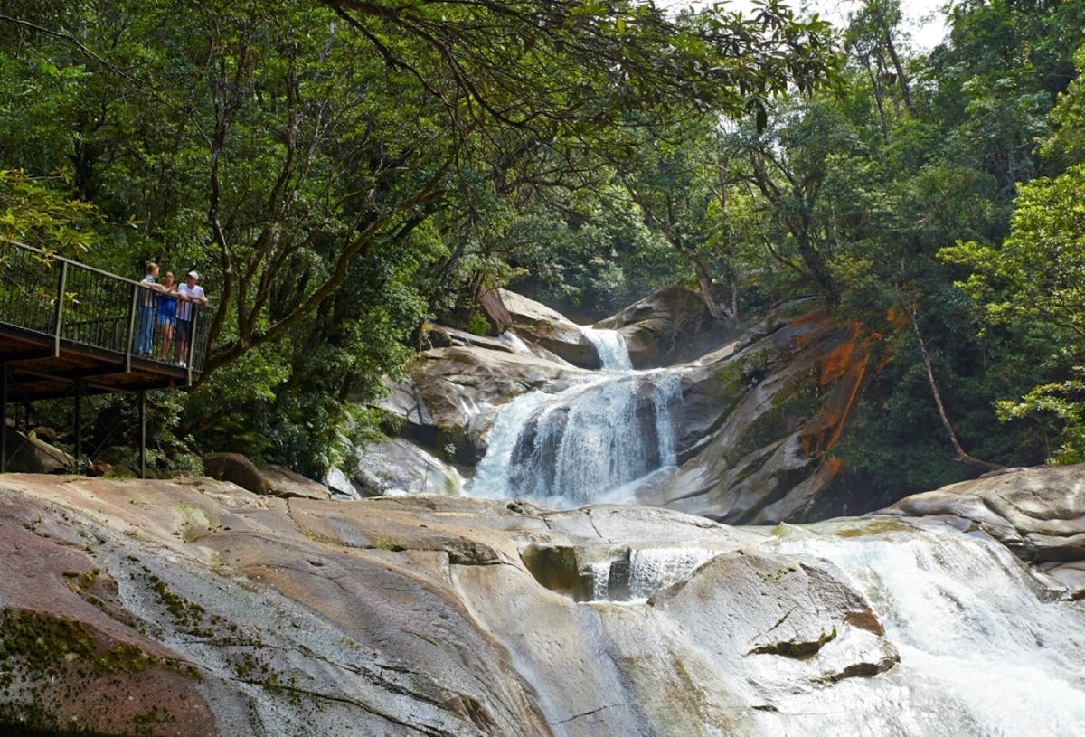 Three people standing at a lookout looking at waterfall.