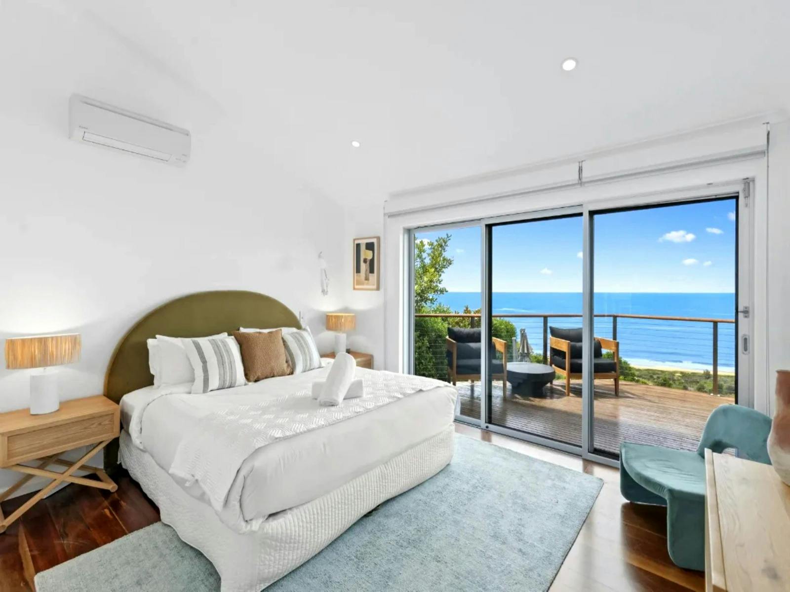 A masters bedroom with breathtaking ocean views from large windows.
