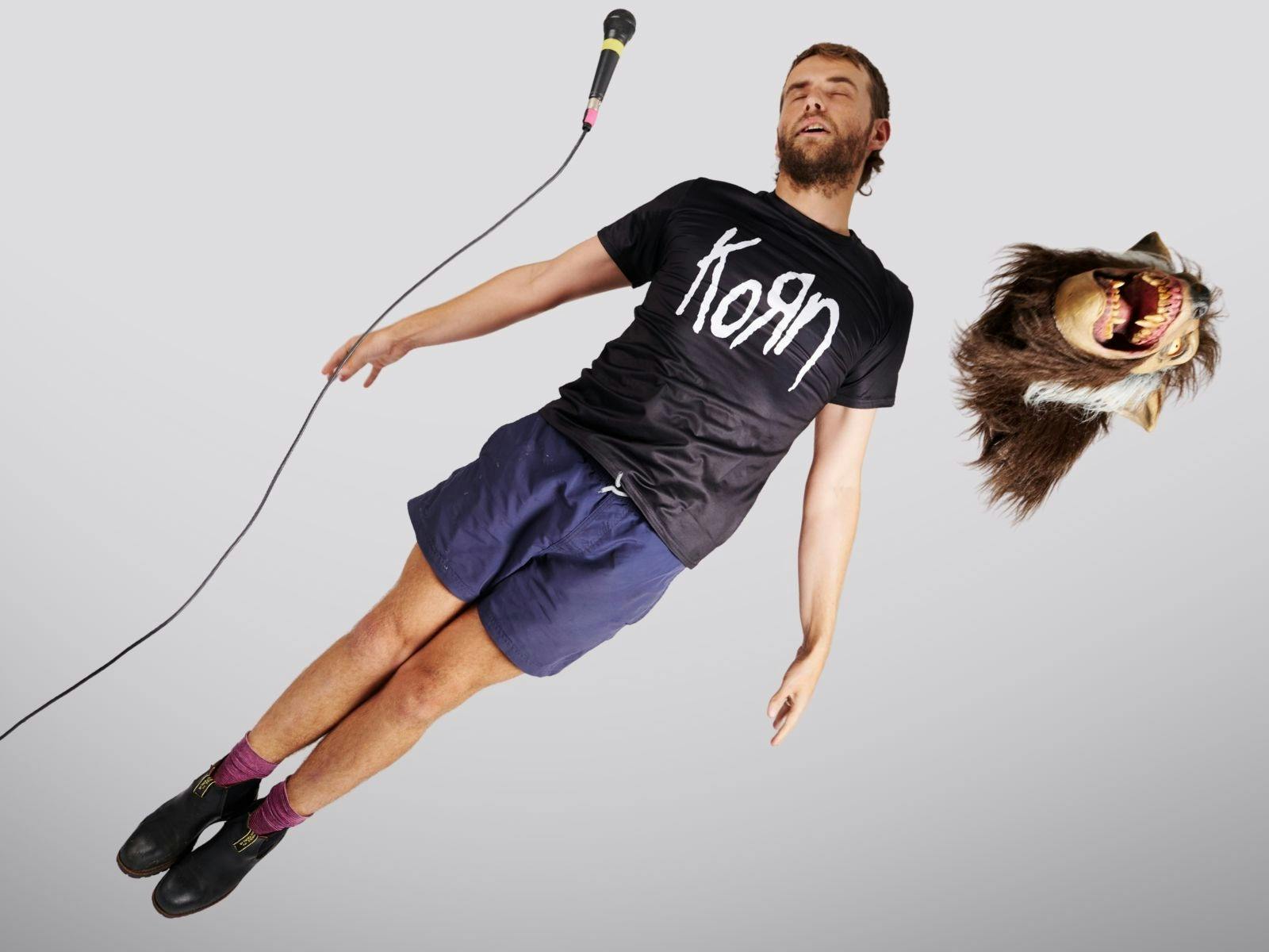 A guy floating through the air with a microphone and werewolf mask