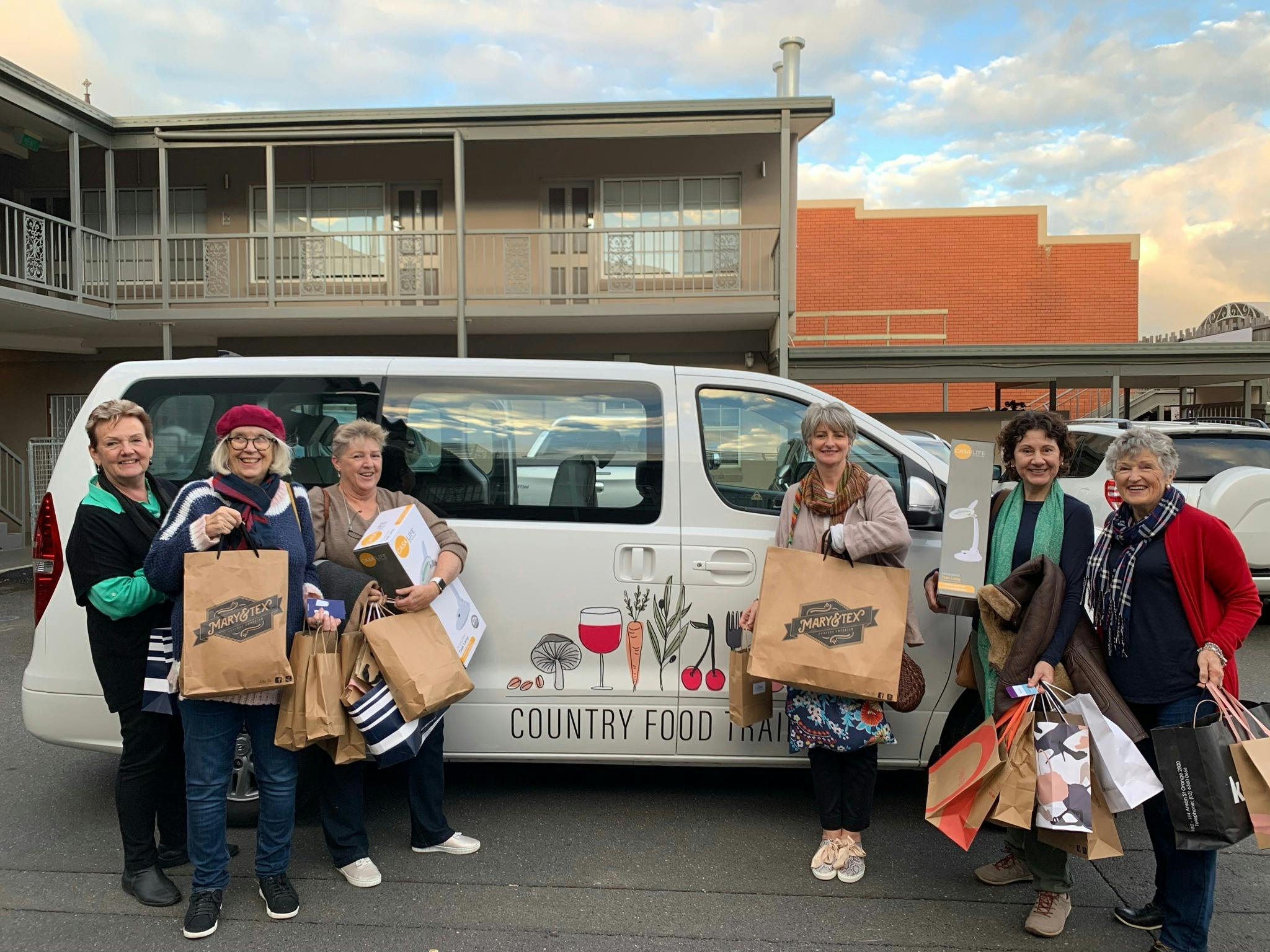 6 ladies with shopping bags standing in front of van