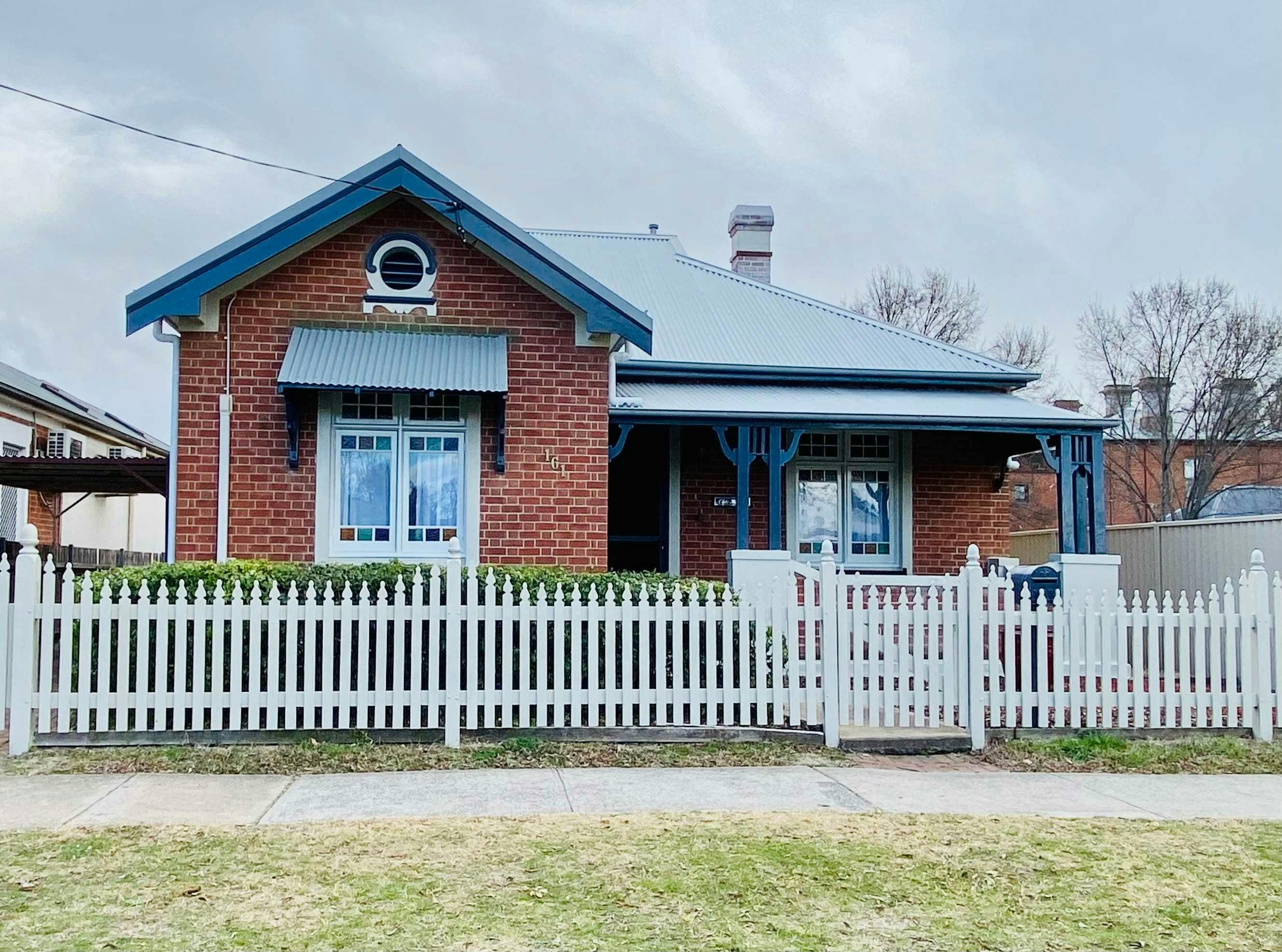 Red brick home with blue details out the front of the home