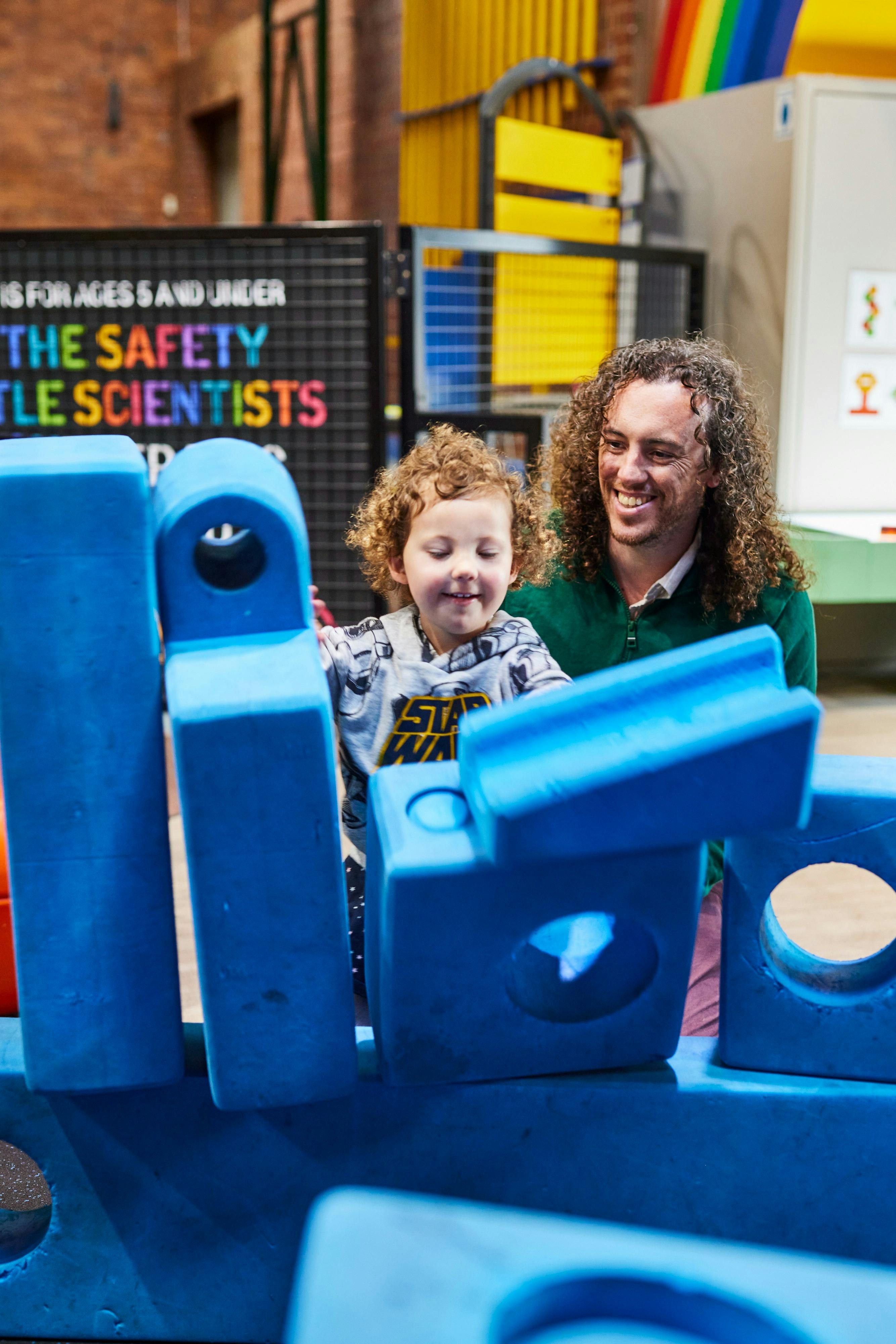 Father helping toddler build blocks in the under 5's playspace