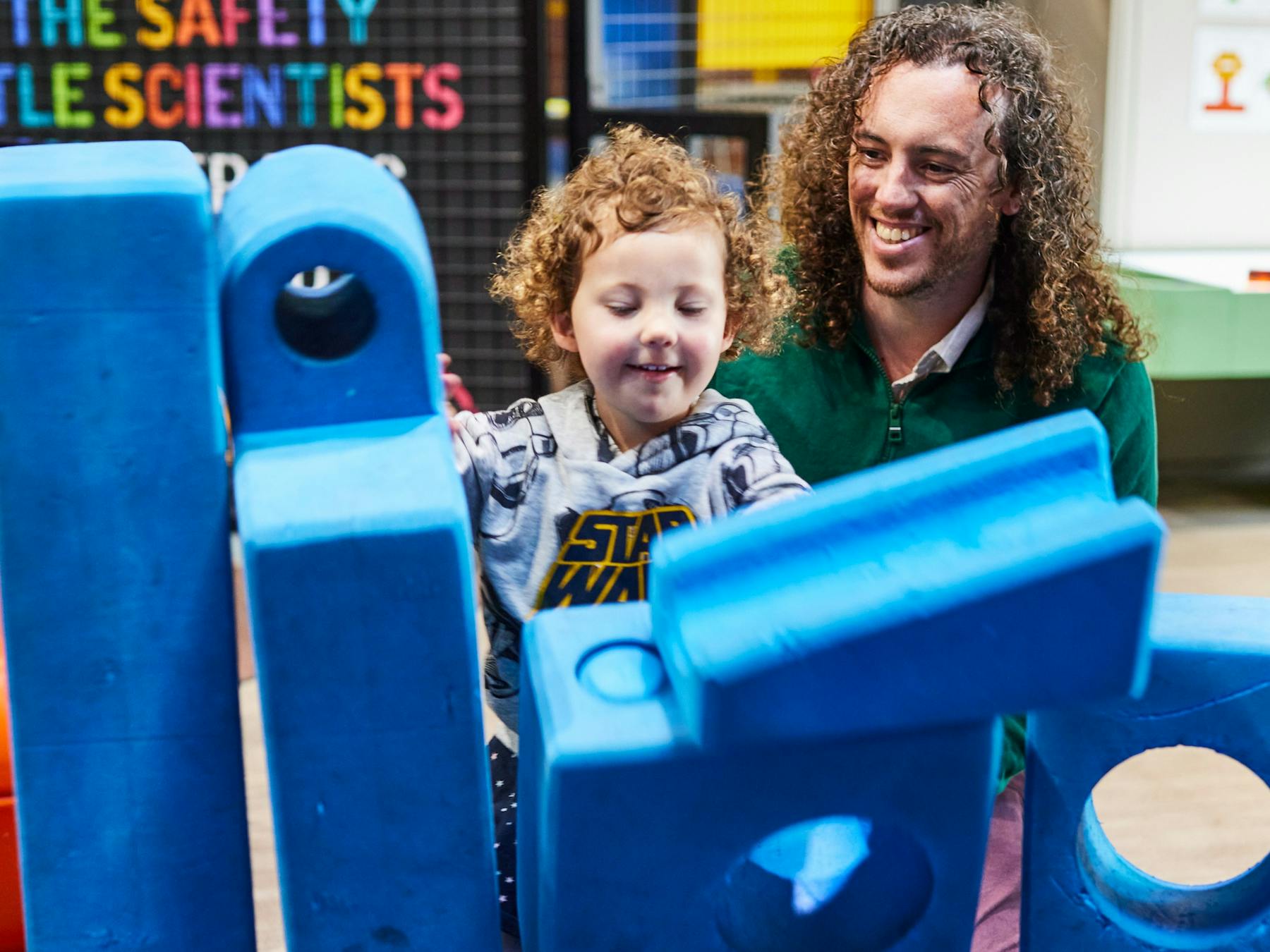 Father helping toddler build blocks in the under 5's playspace