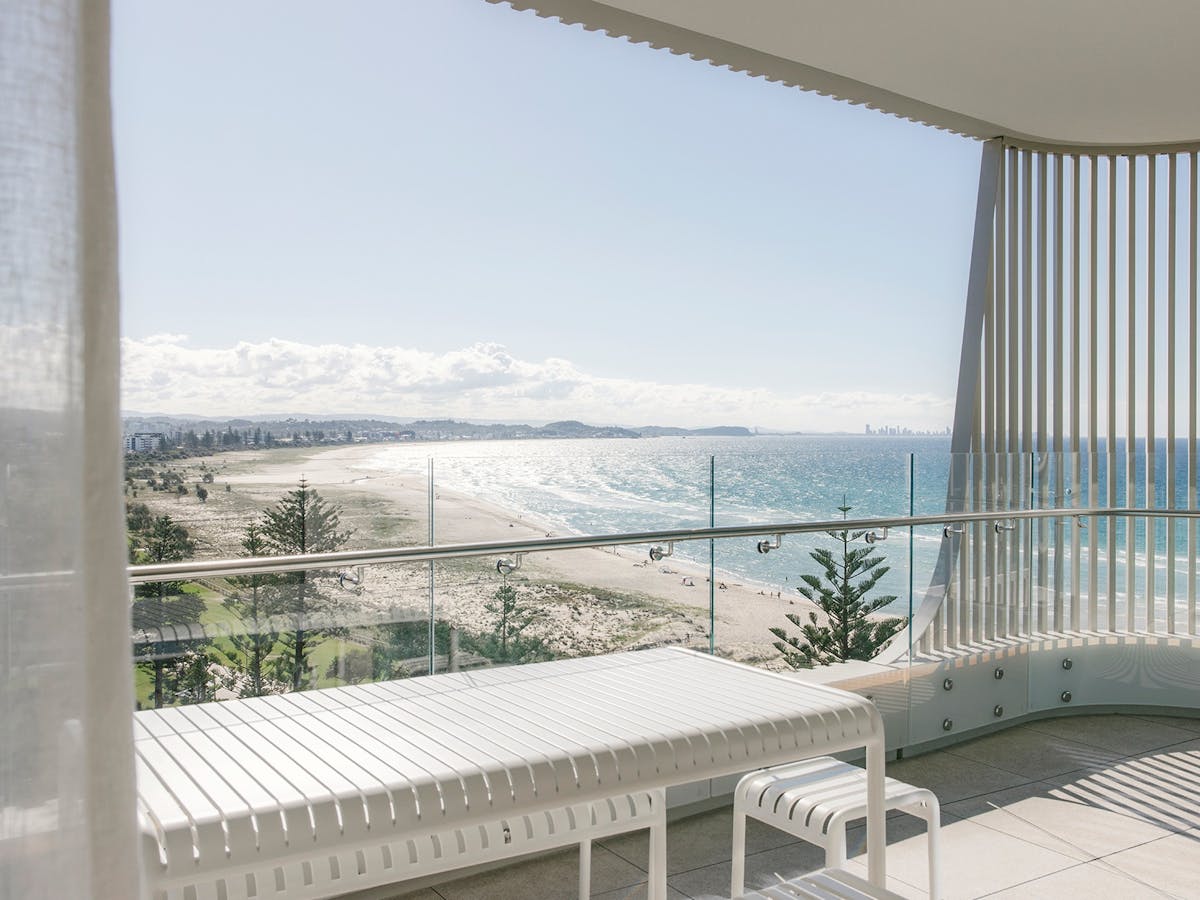 Kirra Point balcony with dining table and sweeping coastal views toward Surfers Paradise skyline