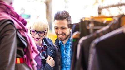 lady and a man smiling at clothing hanging up at an outdoor market