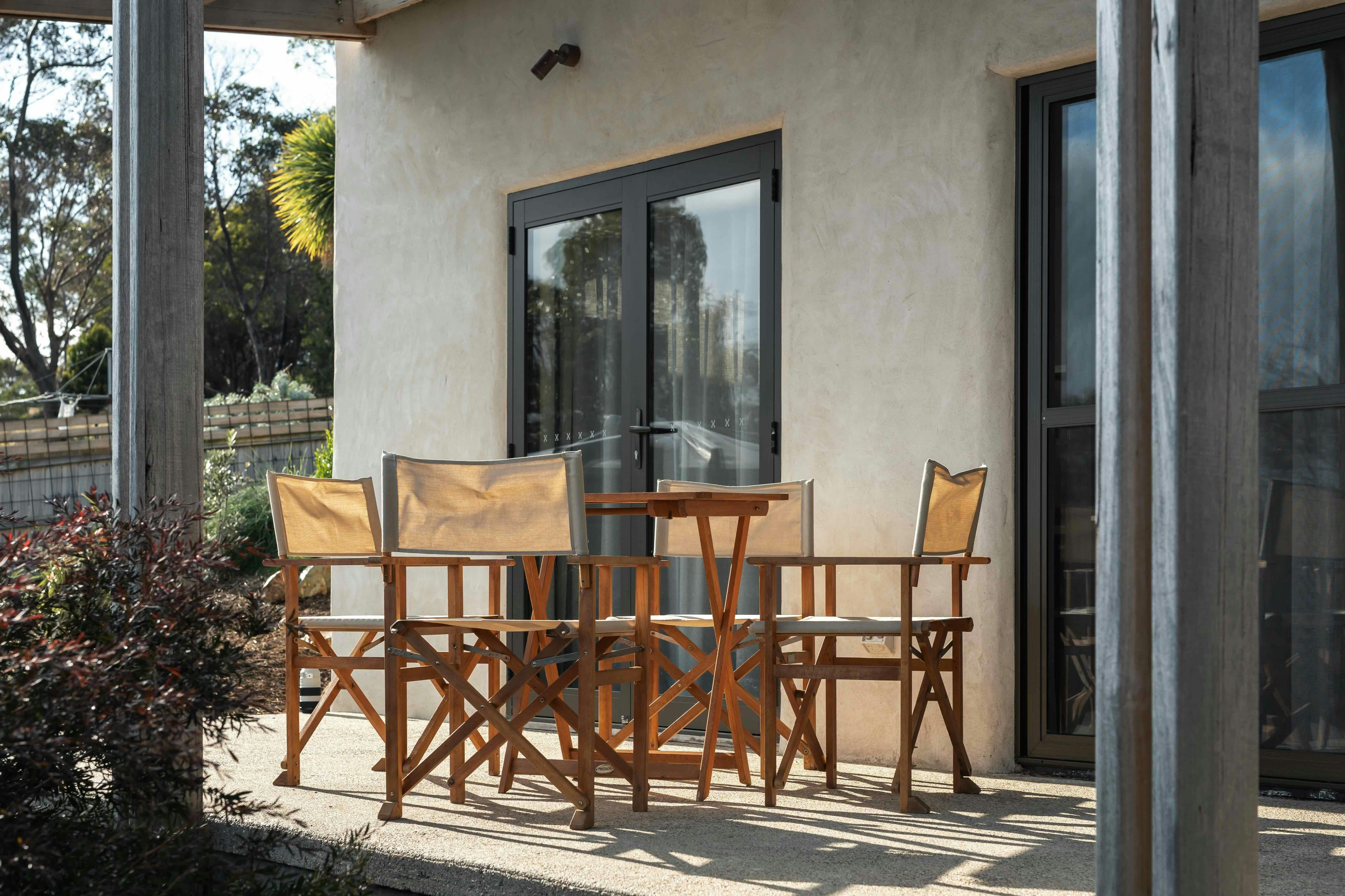 An outdoor dining table with four canvas chairs on a patio area.