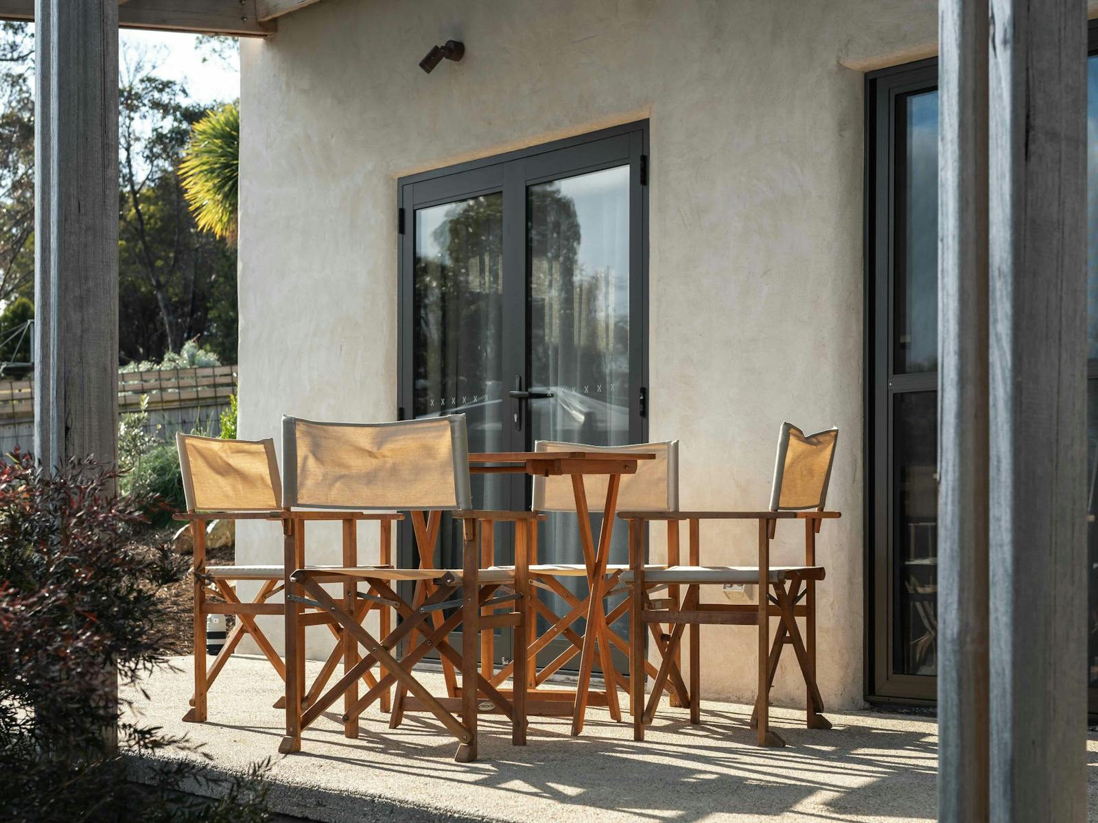 An outdoor dining table with four canvas chairs on a patio area.
