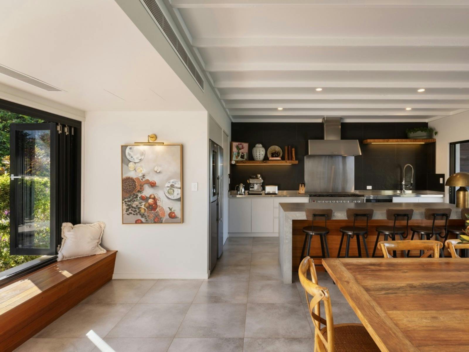 Contemporary kitchen with stone island, timber dining table and premium appliances.