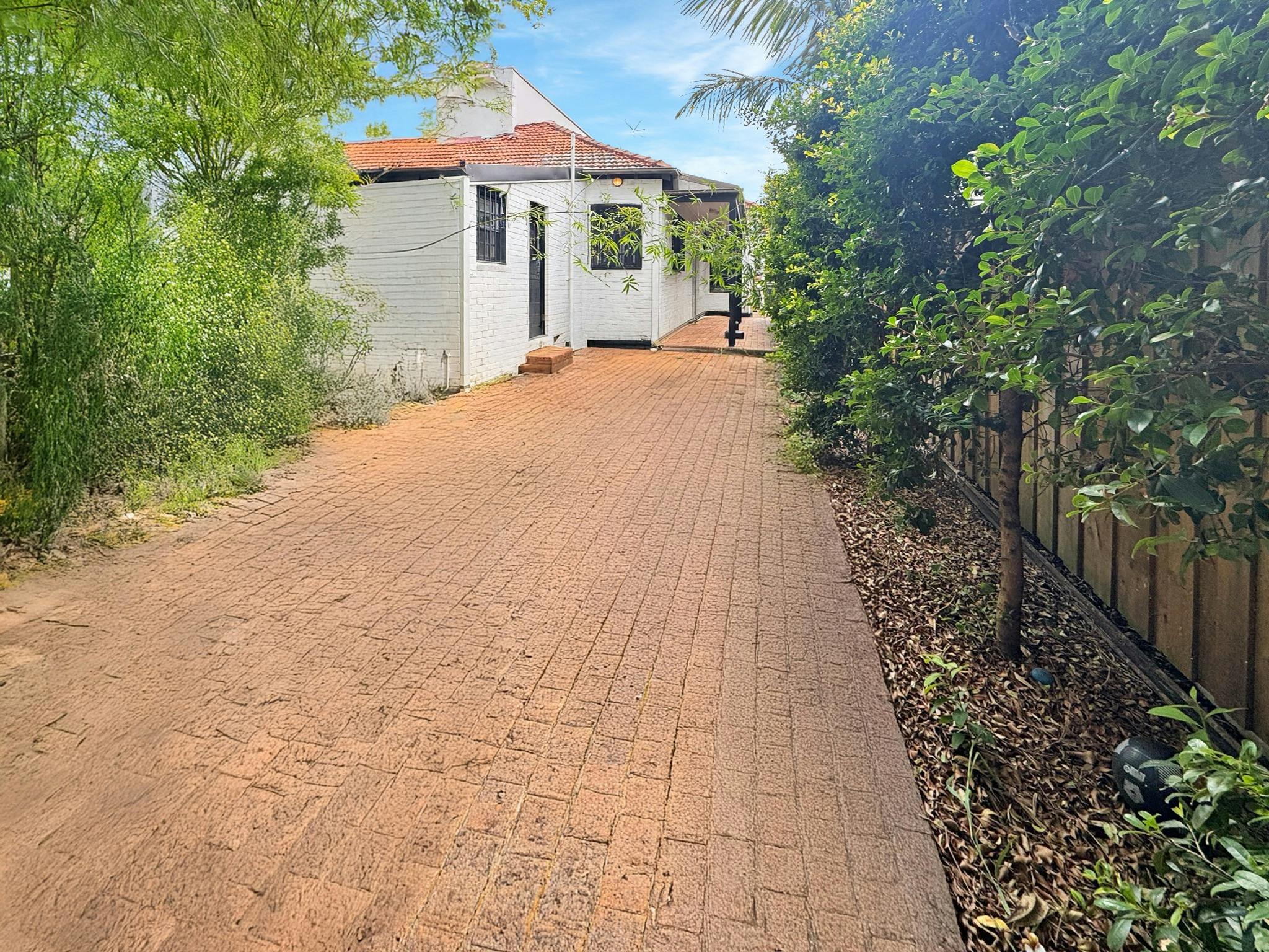 一條小路通往一處民宅，周圍綠樹環繞。