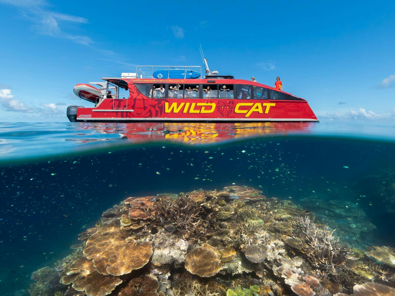 Red Vessel on surface of water with coral reef underneath - half in half out photo