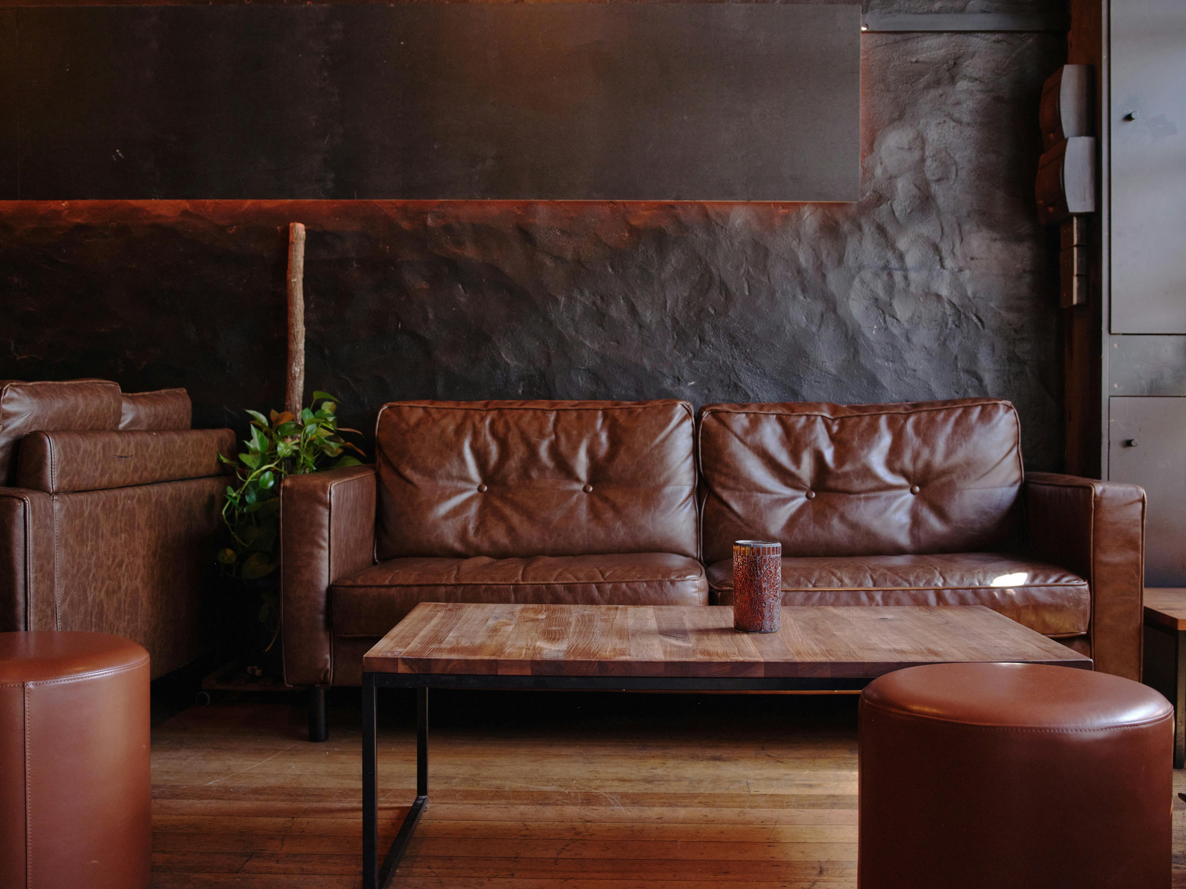 A brown leather couch and low coffee table on hardwood floors in the bar.