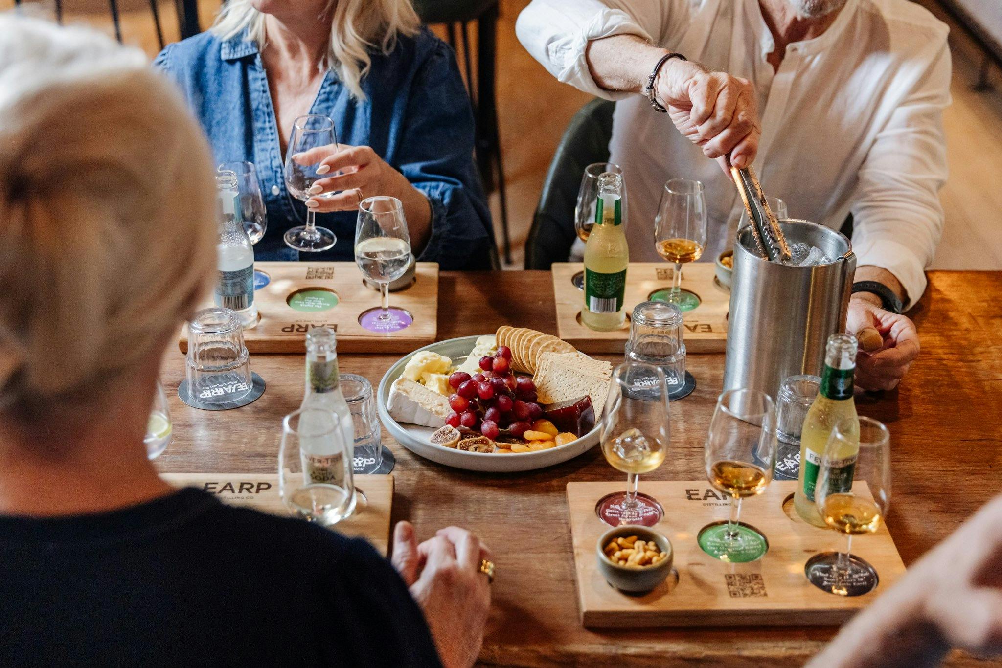 A group of four tasting Earp spirits along with mixers and a cheeseboard