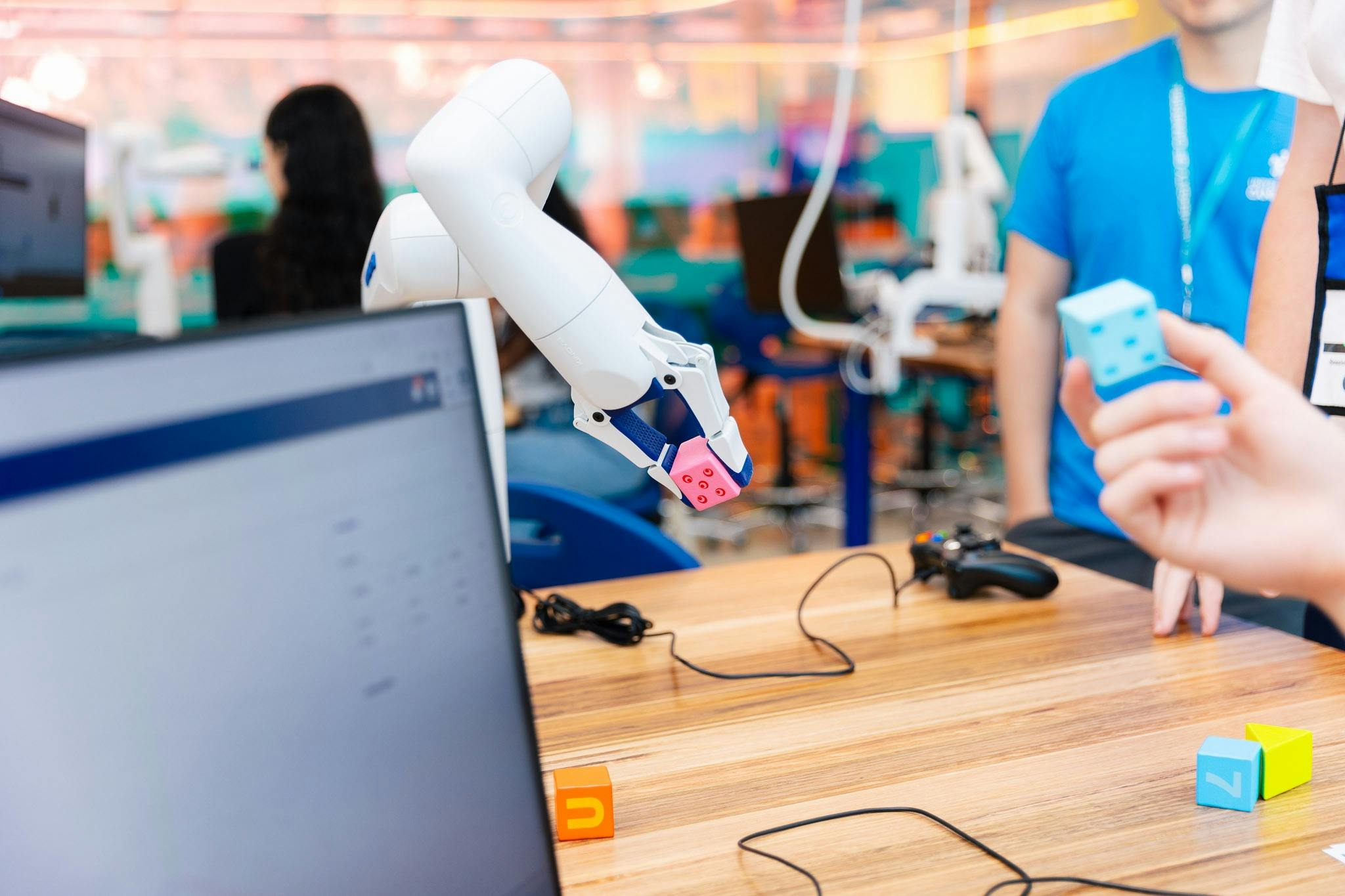 A robotic arm picks up a pink dice.